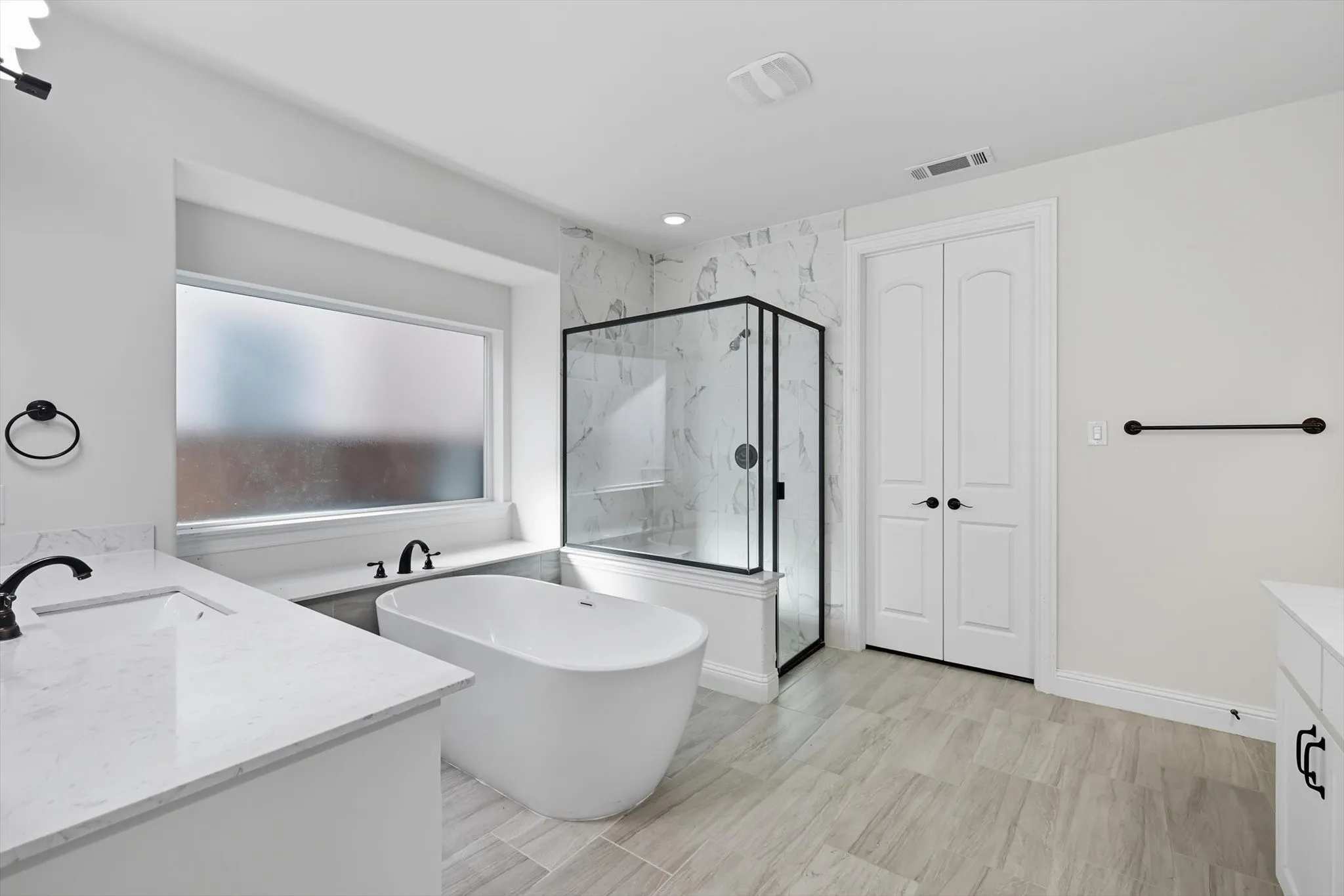 Bathroom with vanity, a soaking tub, and a marble finish shower