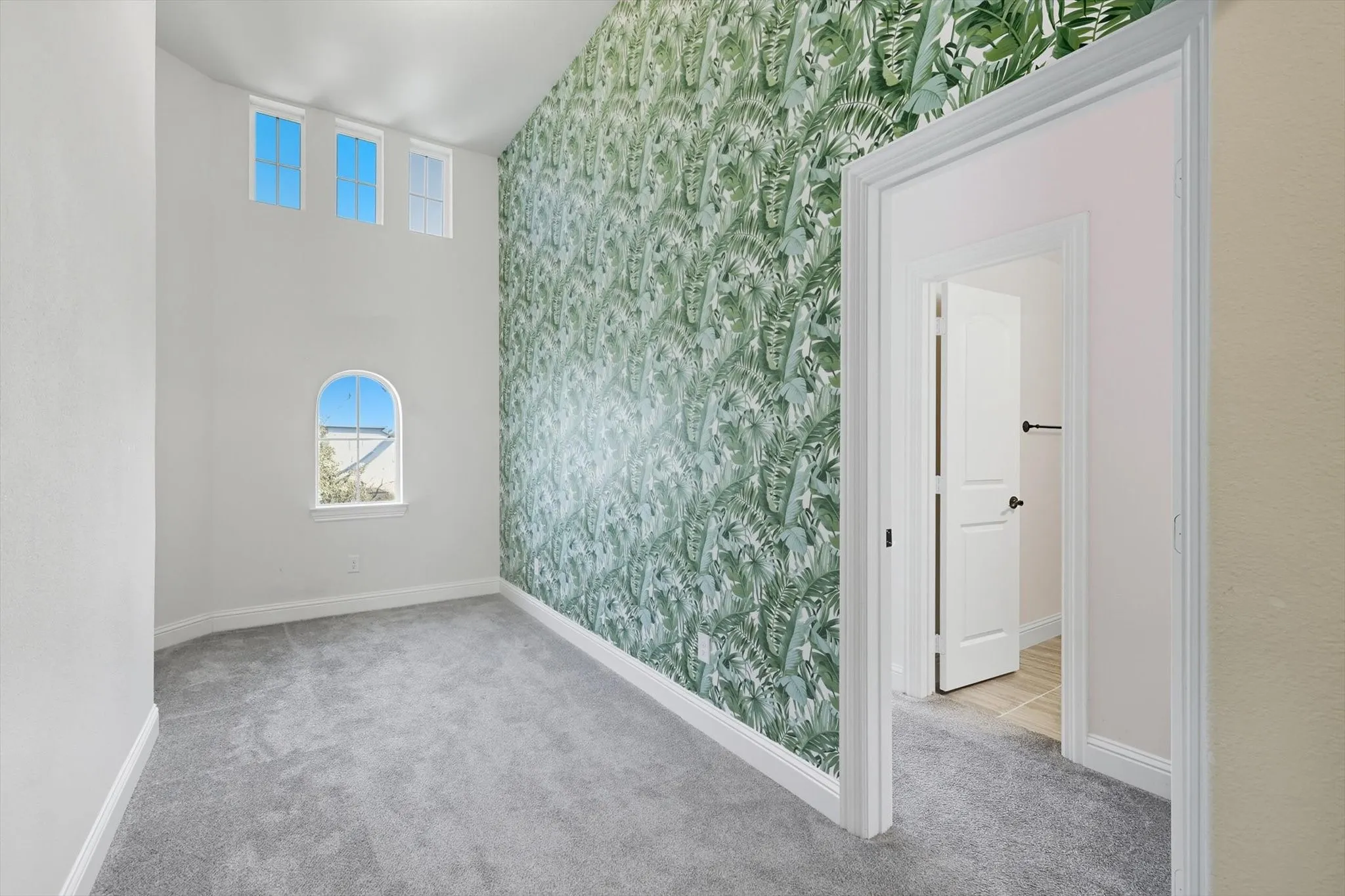 Spare room featuring wallpapered walls, light carpet, and healthy amount of natural light