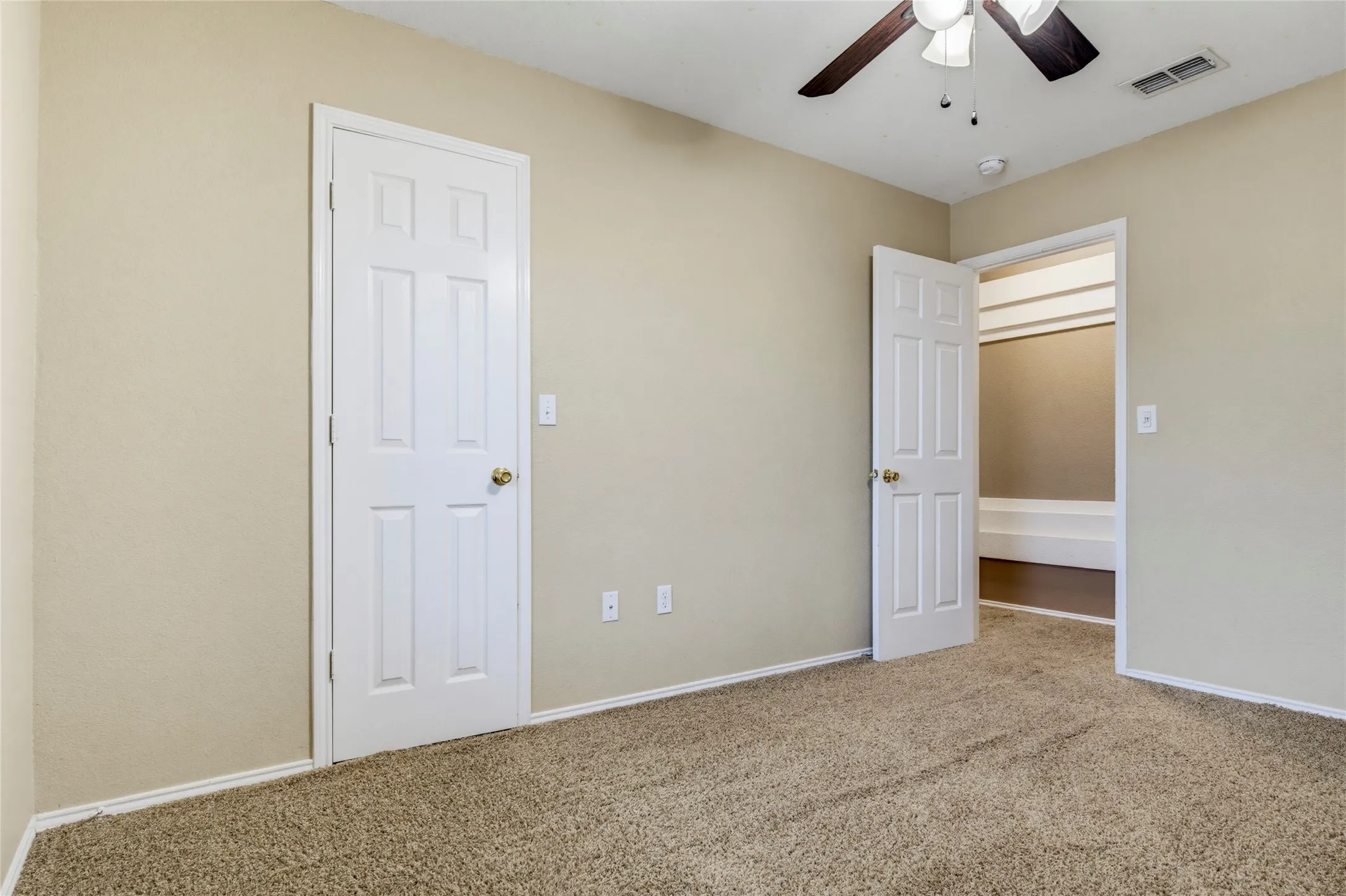 Neutral wall paint, plush carpet flooring, ceiling fan with light fixture, paneled interior doors, and closet with shelving