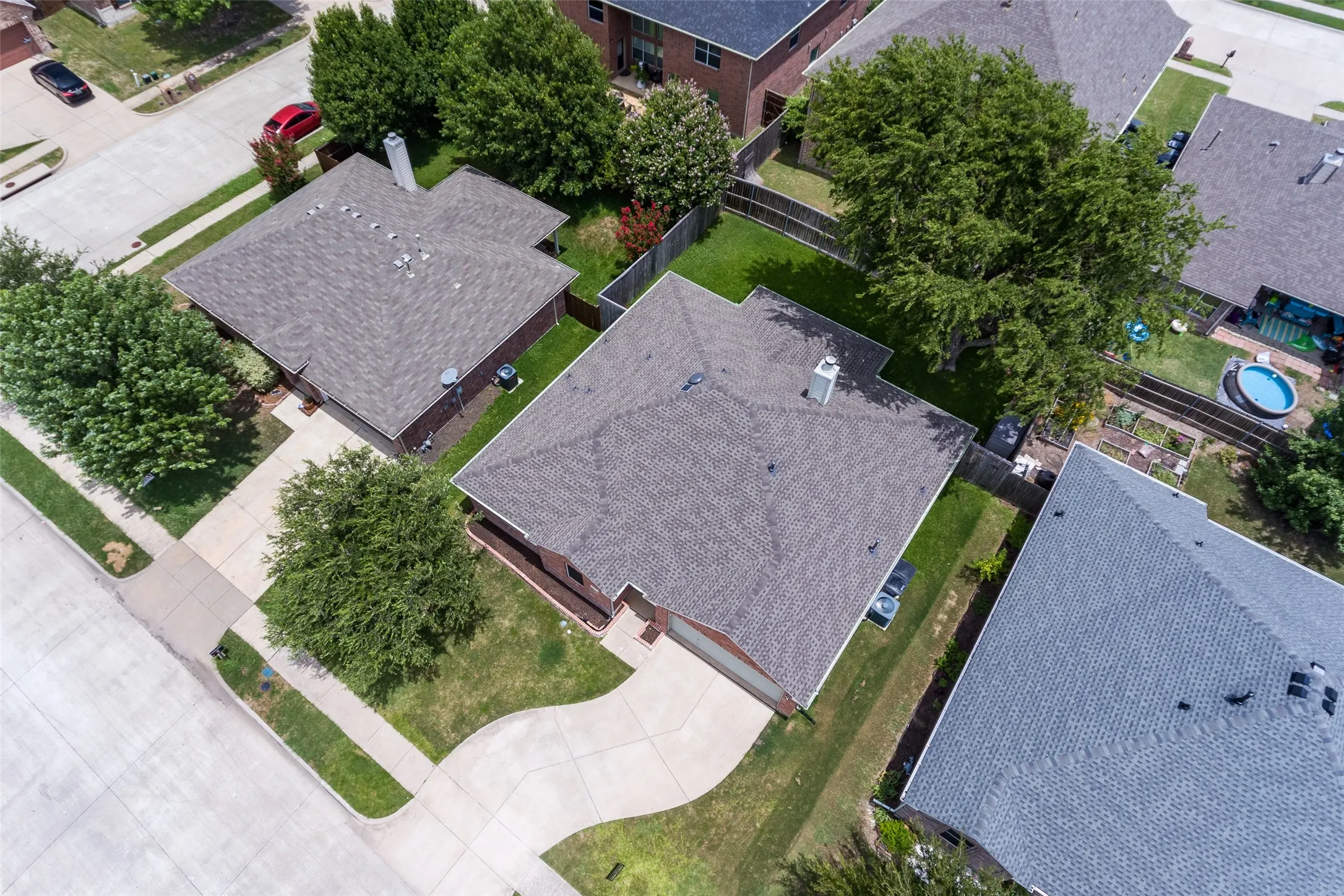 Asphalt shingle roof, concrete driveway, mature trees, manicured lawns, and brick exterior