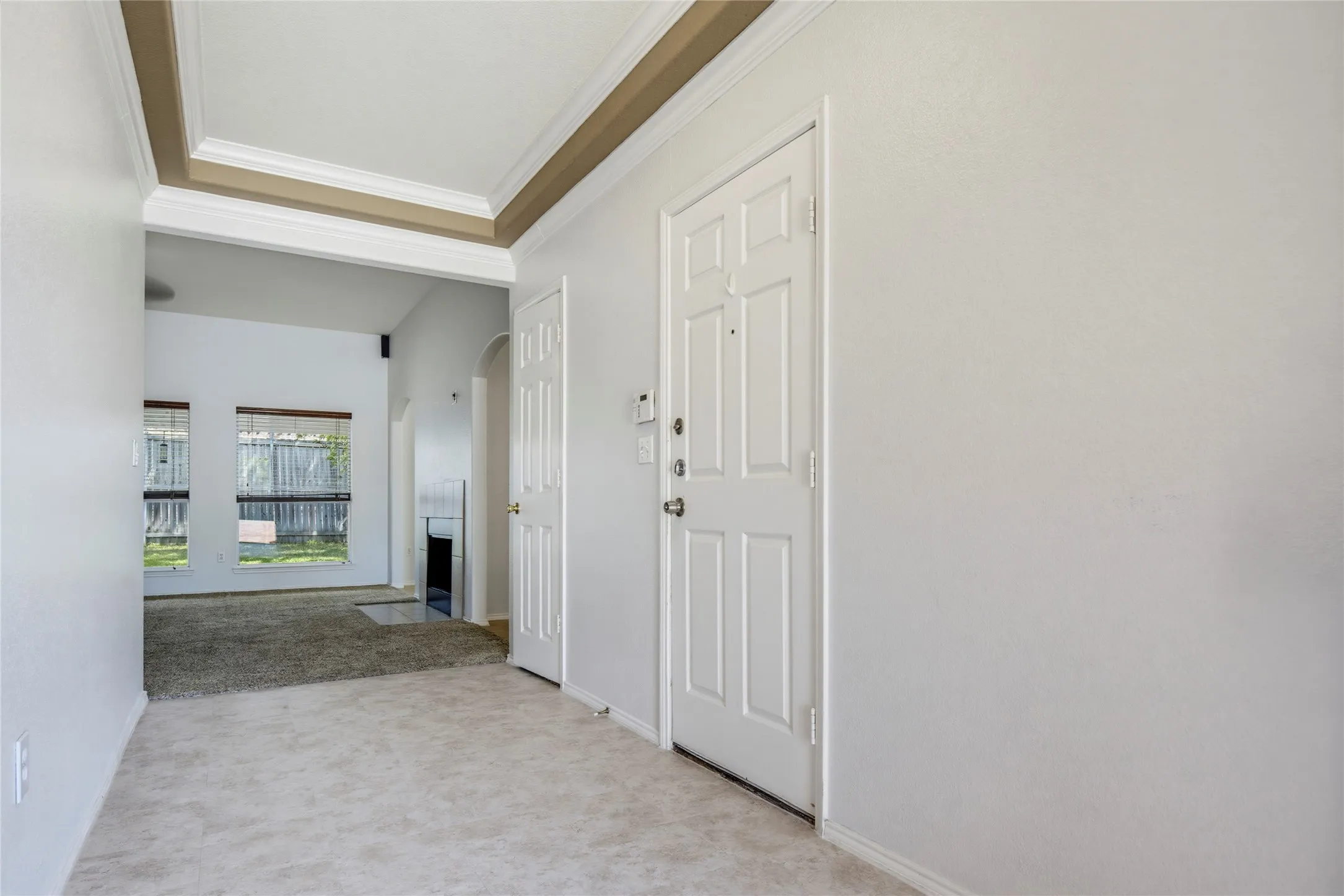 Tray ceiling with crown molding details, paneled interior doors, and mixed flooring materials