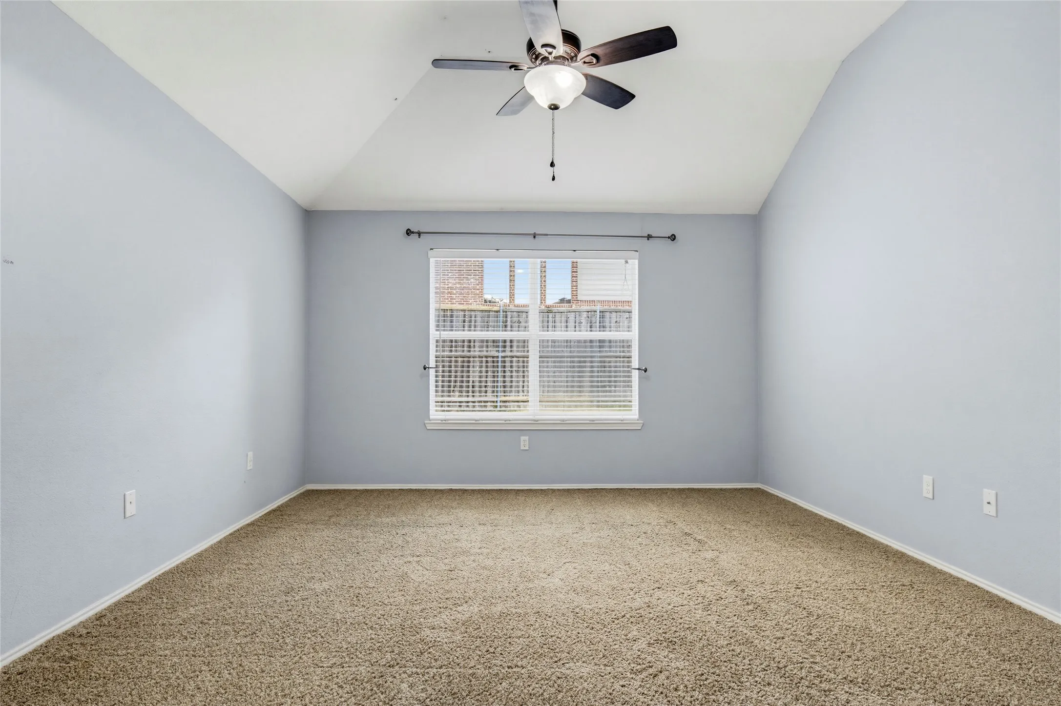 Vaulted ceiling with a ceiling fan light fixture, window with horizontal blinds, and carpeted flooring