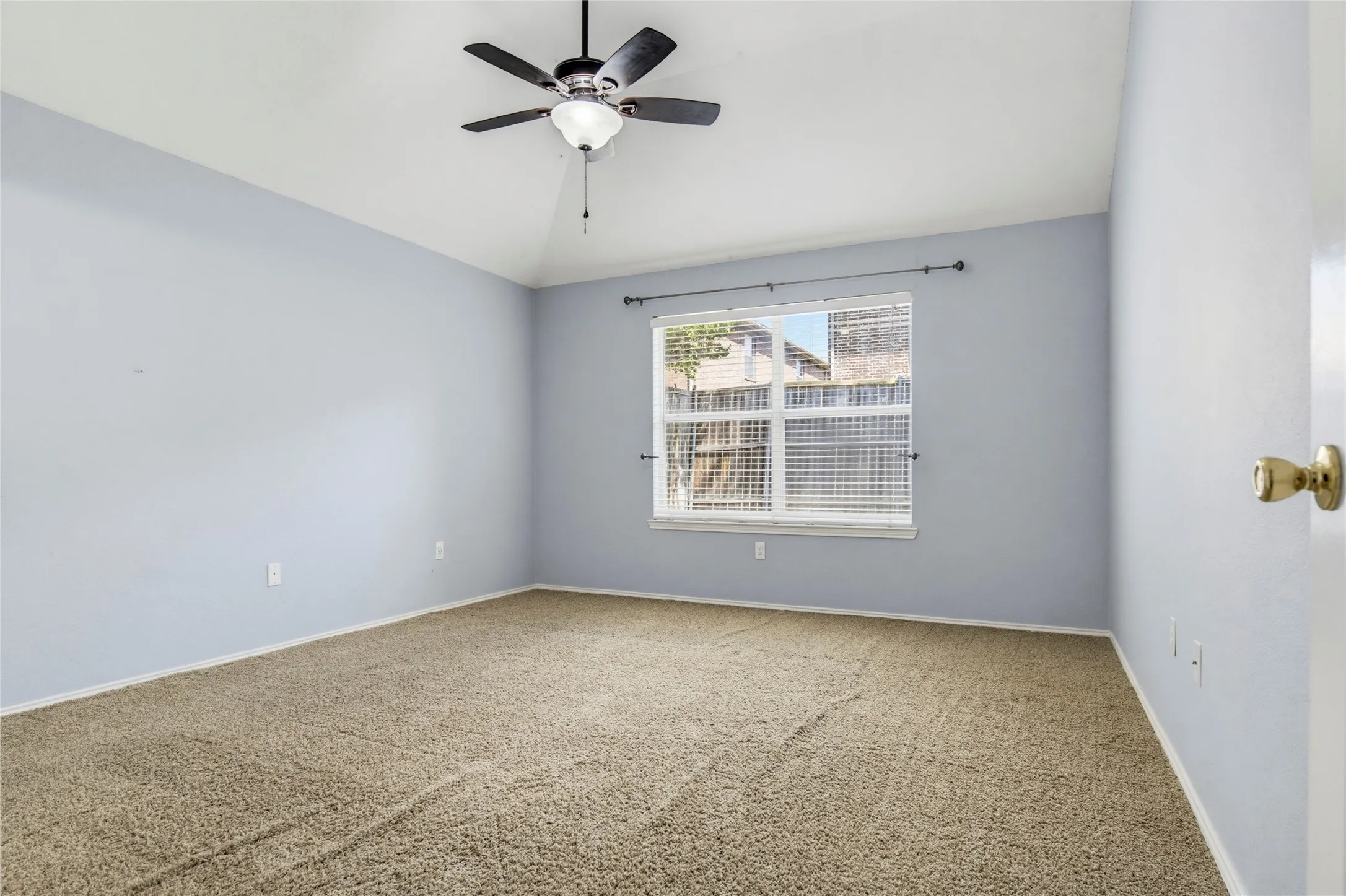 Carpeted room featuring a ceiling fan with integrated lighting and a window with horizontal blinds