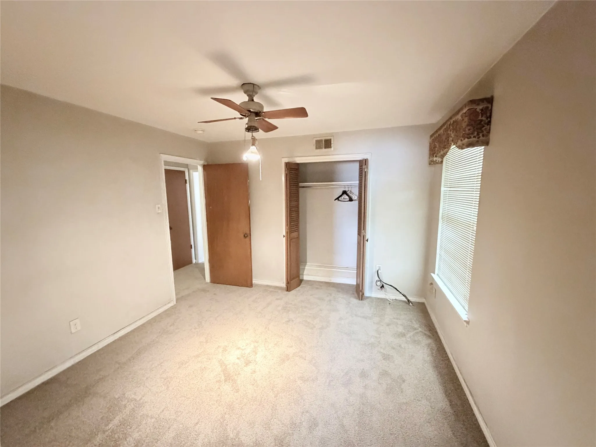Plush carpet flooring, ceiling fan with integrated lighting, and multiple interior doors