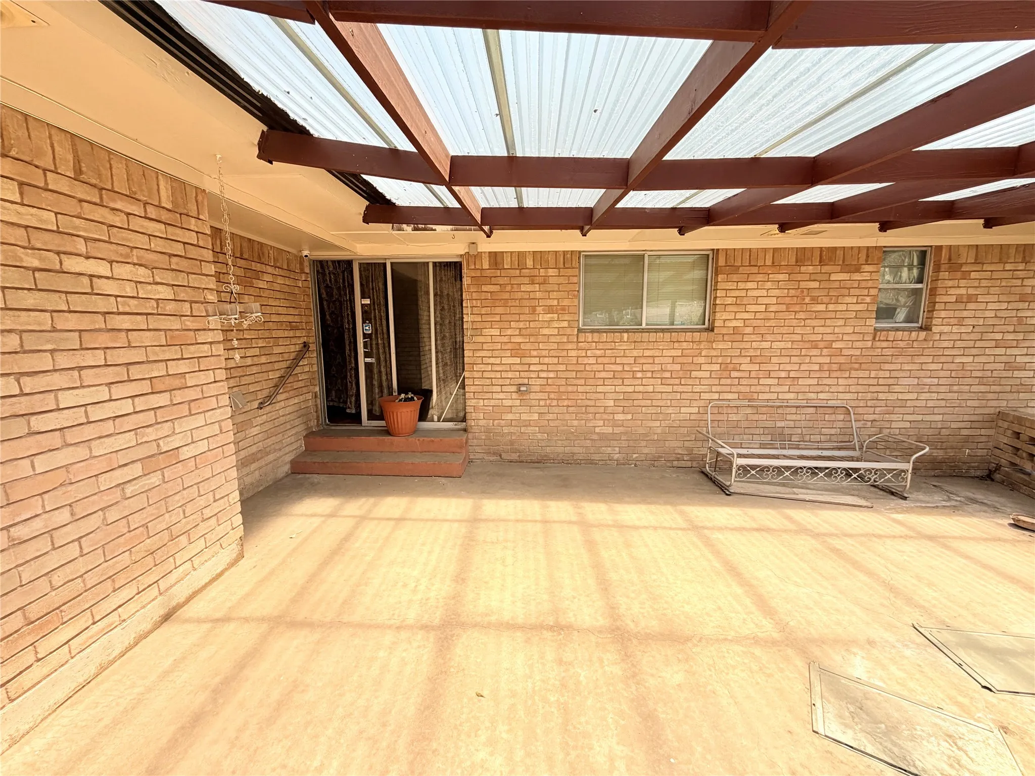 Covered patio with a translucent panel roof, brick exterior, and concrete flooring