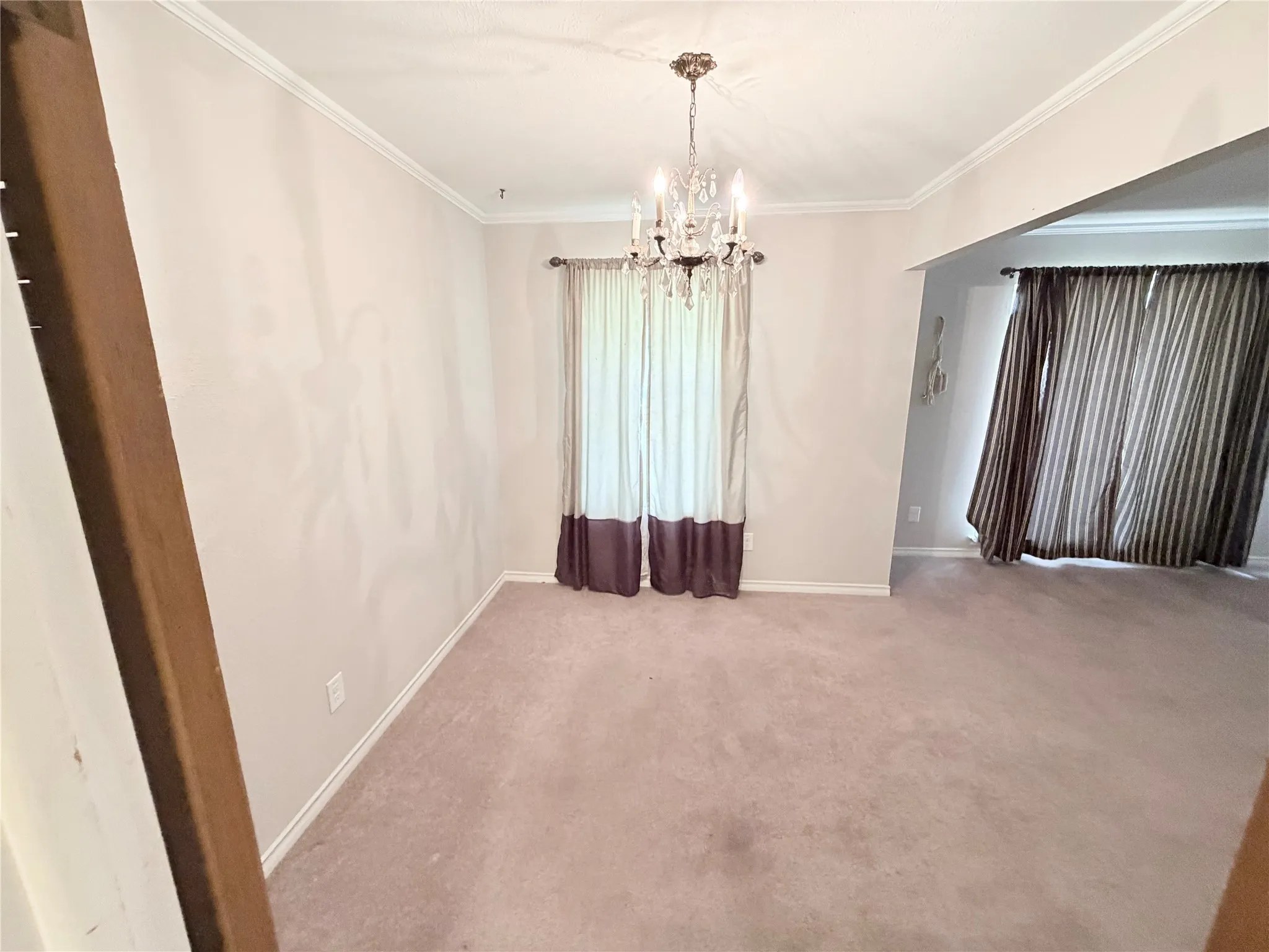 Crown molding, chandelier, wall-to-wall carpeting, and an arched entryway