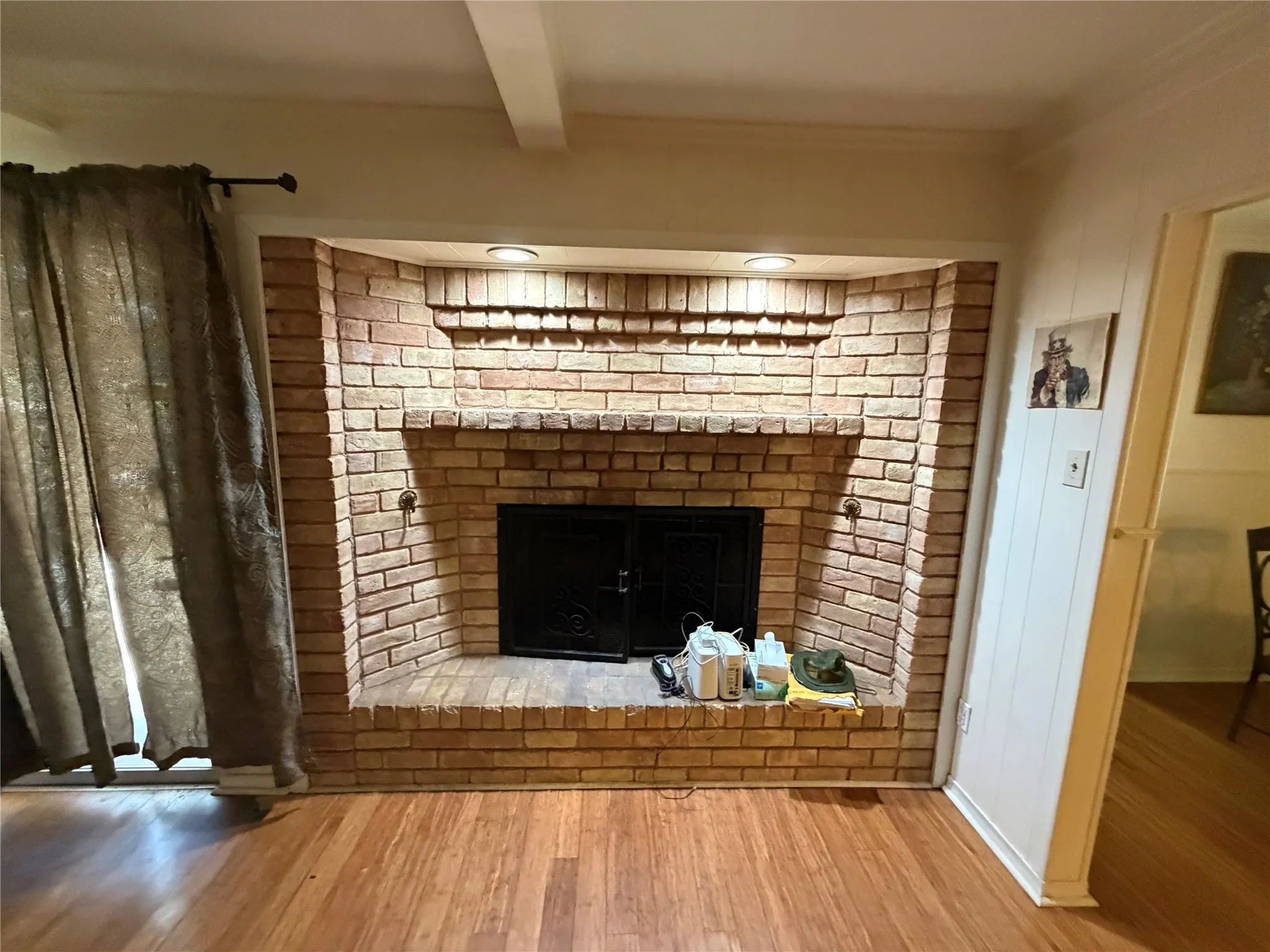 Brick fireplace with a black metal screen, integrated recessed lighting, and wood-finish flooring
