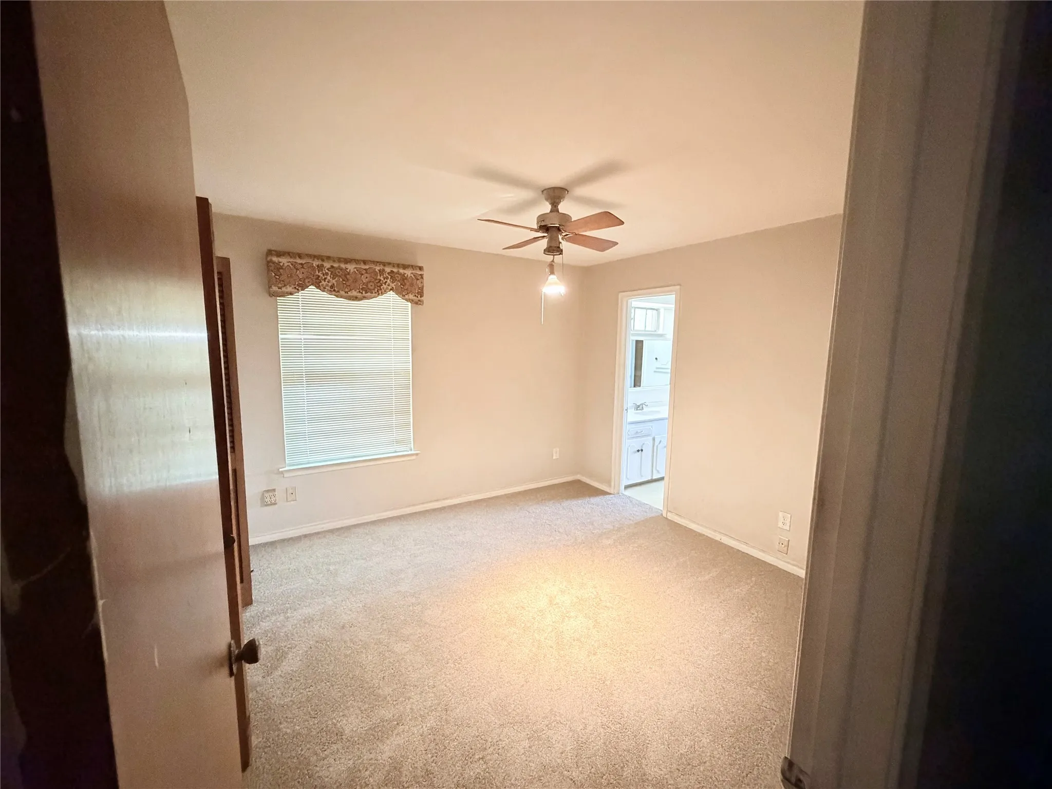 Wall-to-wall carpeting with a ceiling fan light fixture and window with blinds