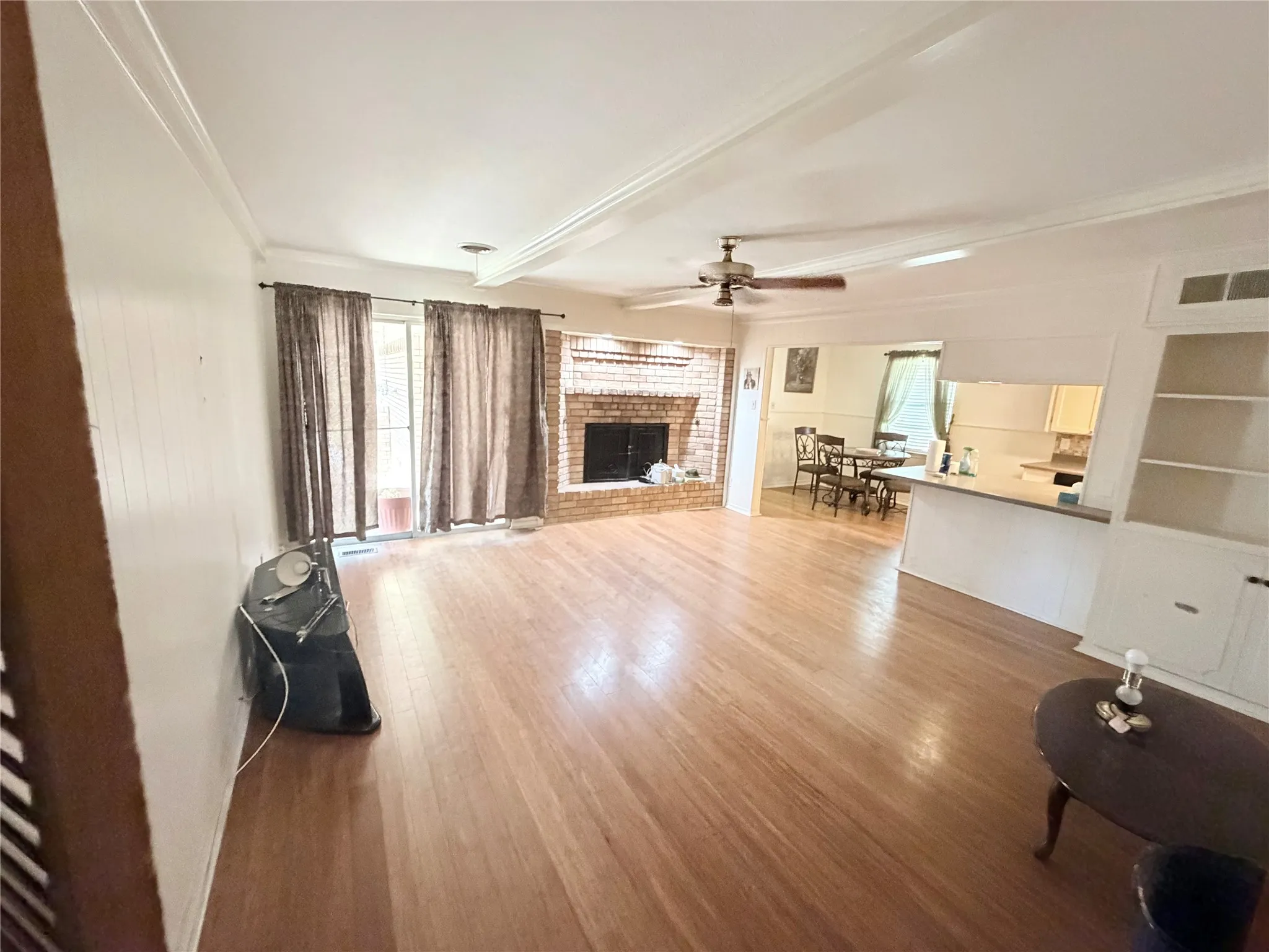 Hardwood flooring throughout, brick fireplace, ceiling fan, crown molding, and built-in shelving