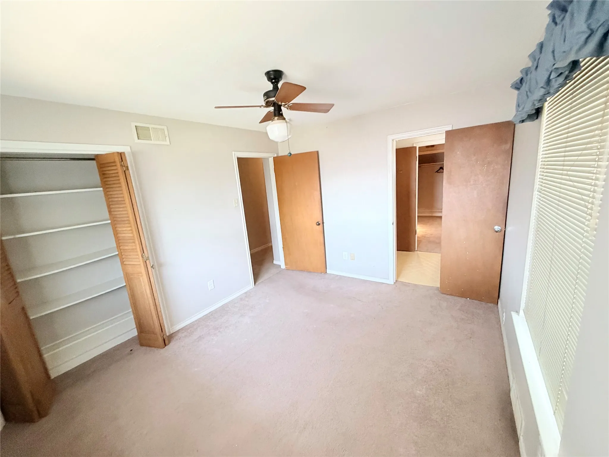 Recessed shelving, ceiling fan with light fixture, window with blinds, wood-finish interior doors