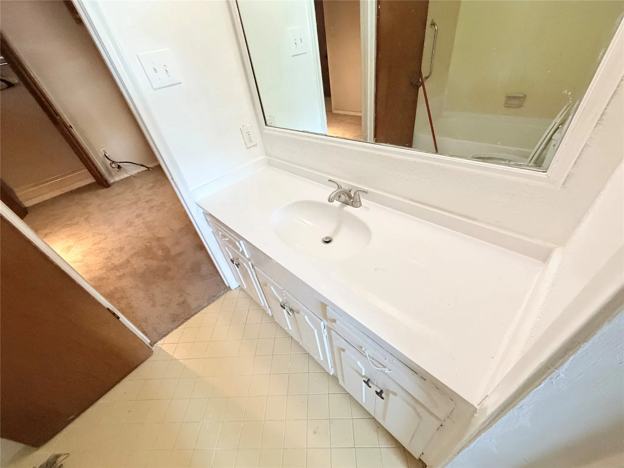 White vanity with integrated sink, chrome faucet, and storage cabinetry with silver-tone hardware