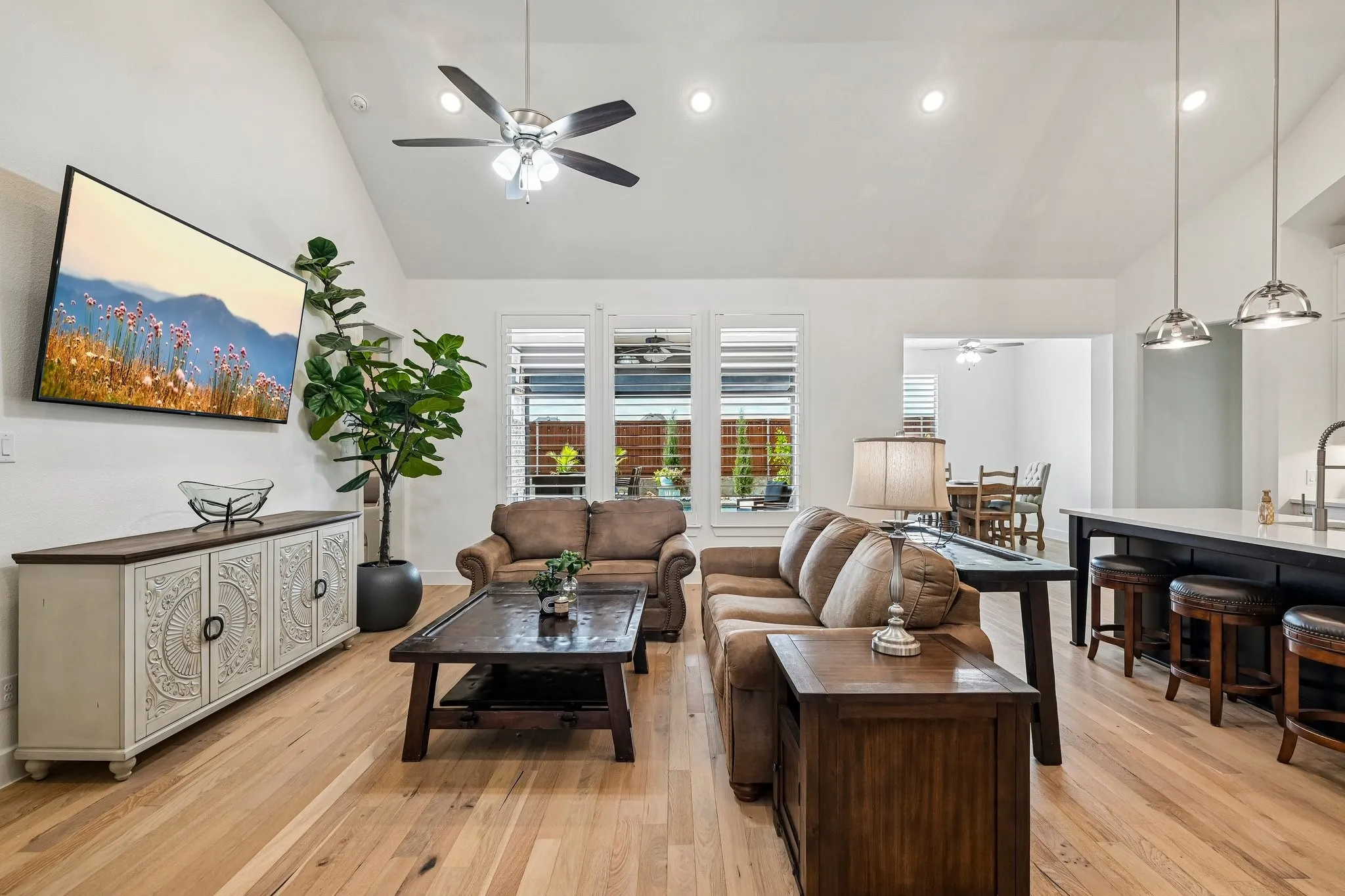 Vaulted ceiling with recessed lighting, wood-finish flooring, plantation shutters, and a kitchen island with pendant lighting