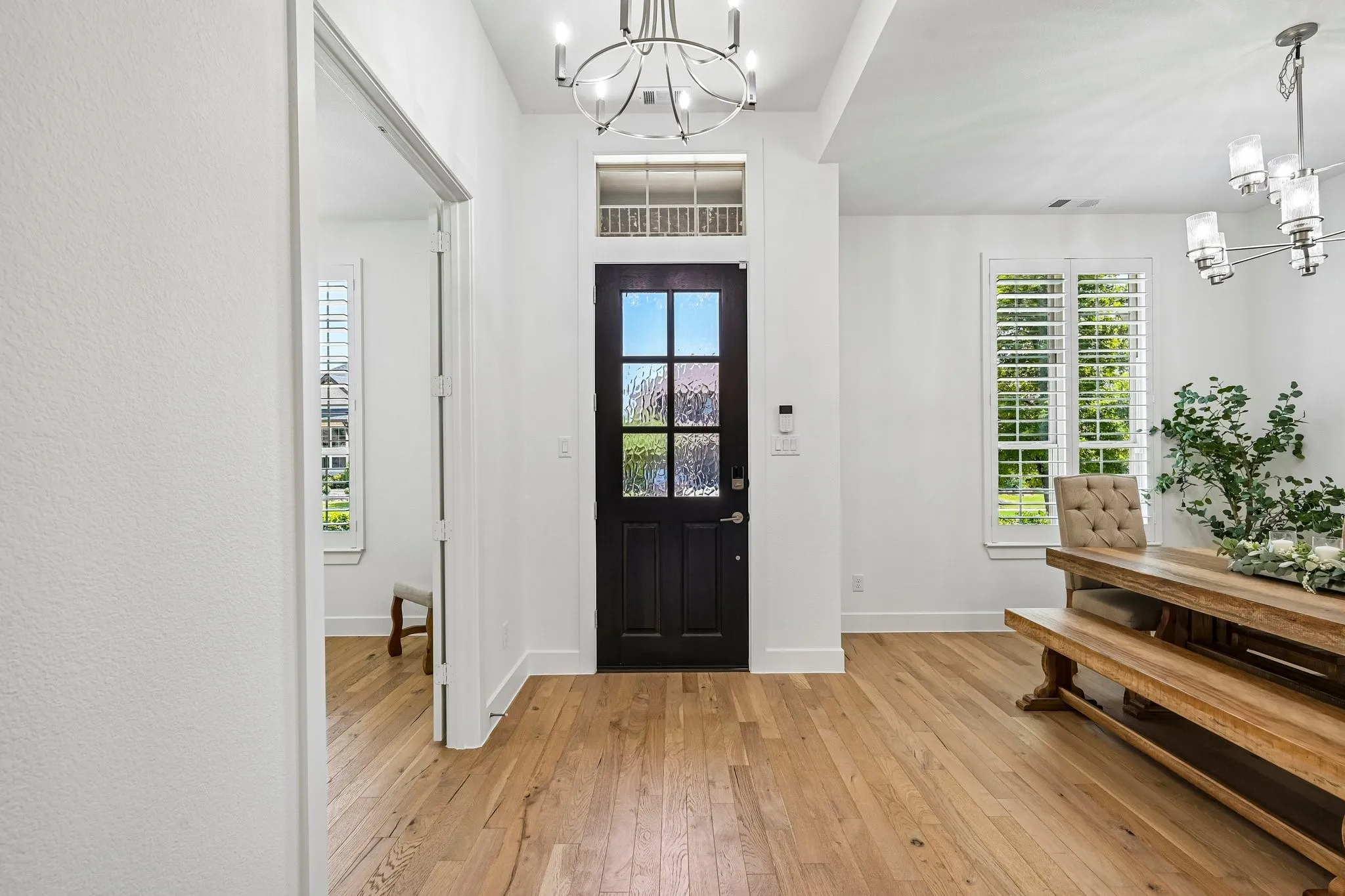 Entry foyer featuring wood-finish flooring, a dark-paneled door with glass inserts, and a transom window