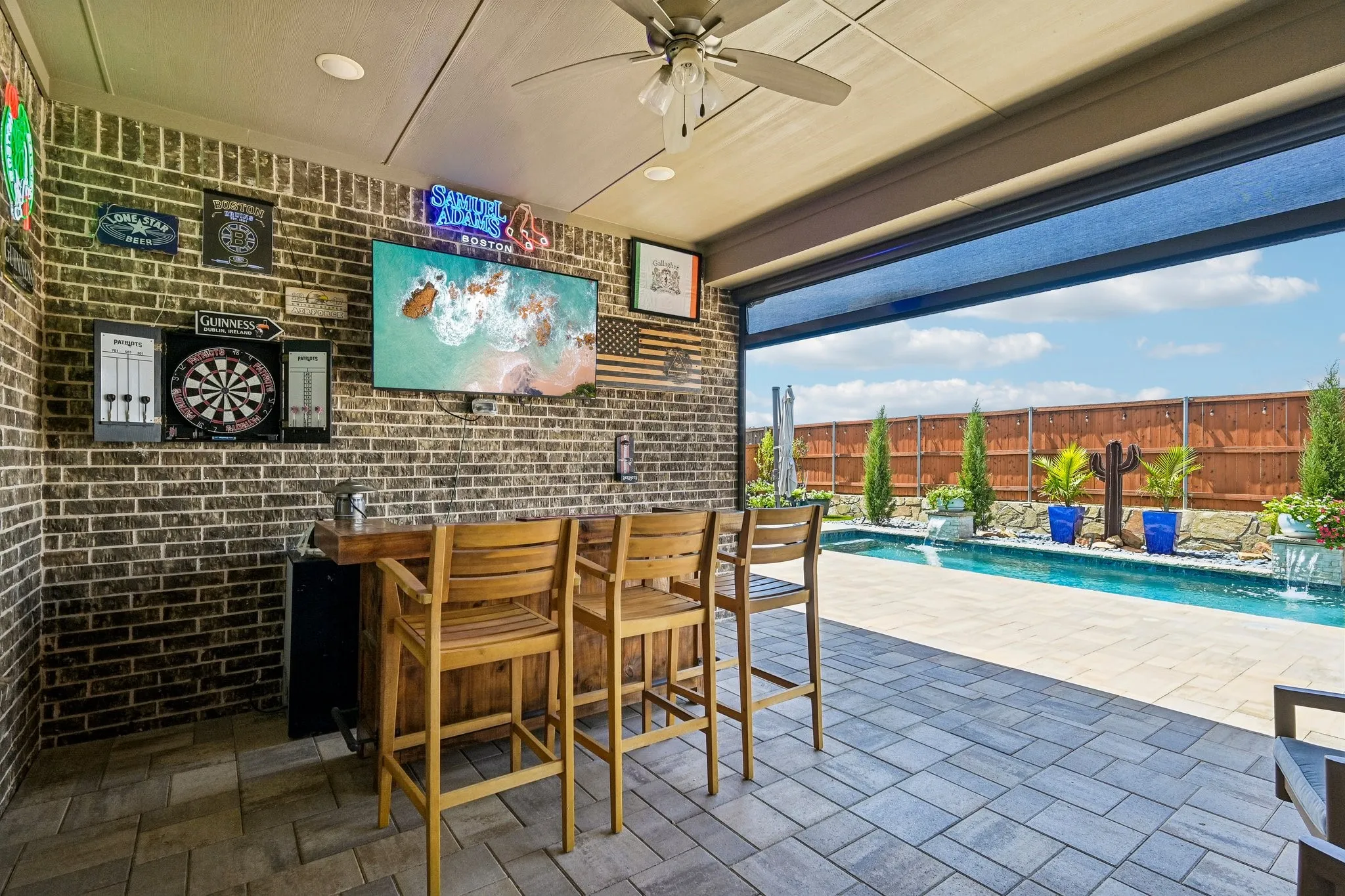 Covered patio featuring brick walls, a built-in bar, and a ceiling fan