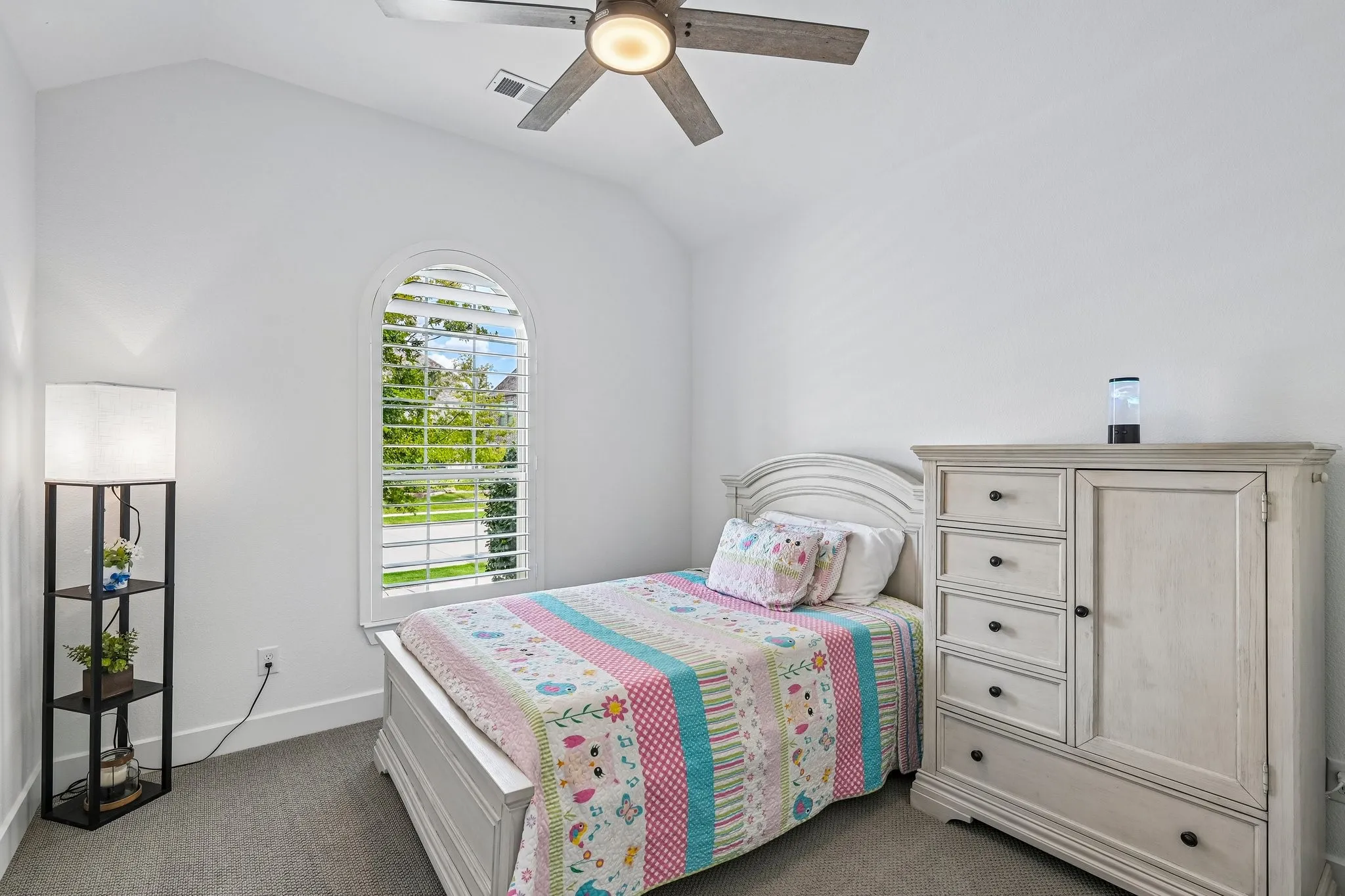 Arched window with plantation shutters, vaulted ceiling, ceiling fan with integrated lighting, and carpeted flooring
