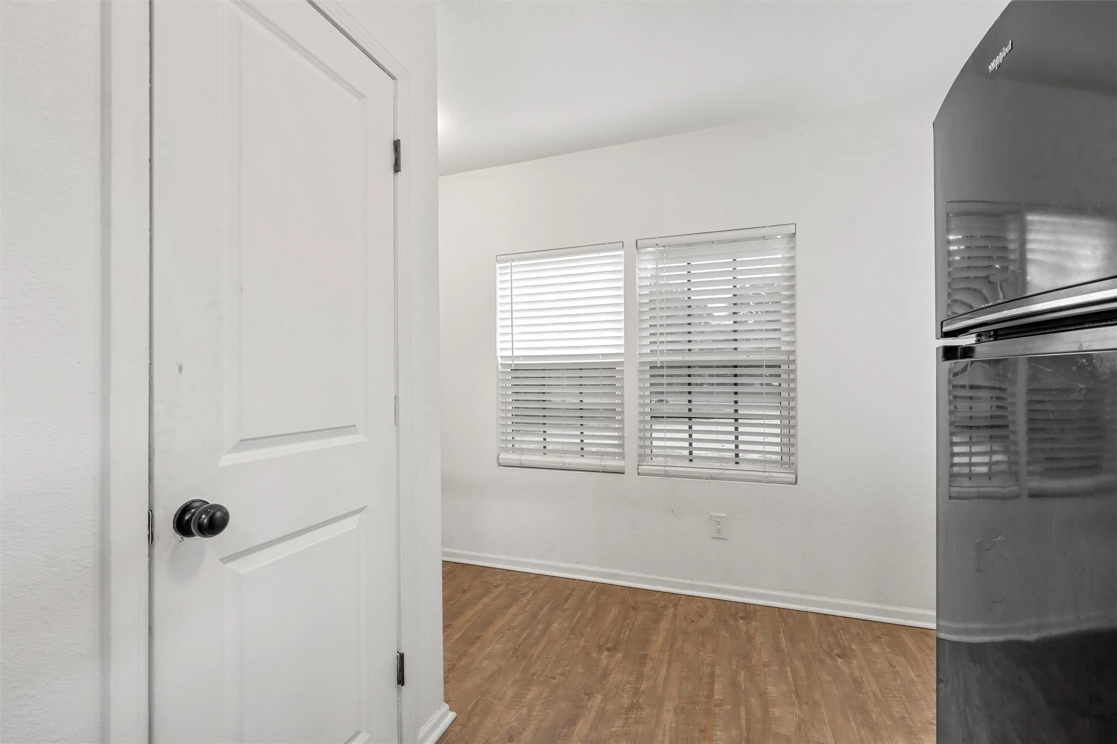 Wood-finish flooring, white walls, and dual windows with blinds