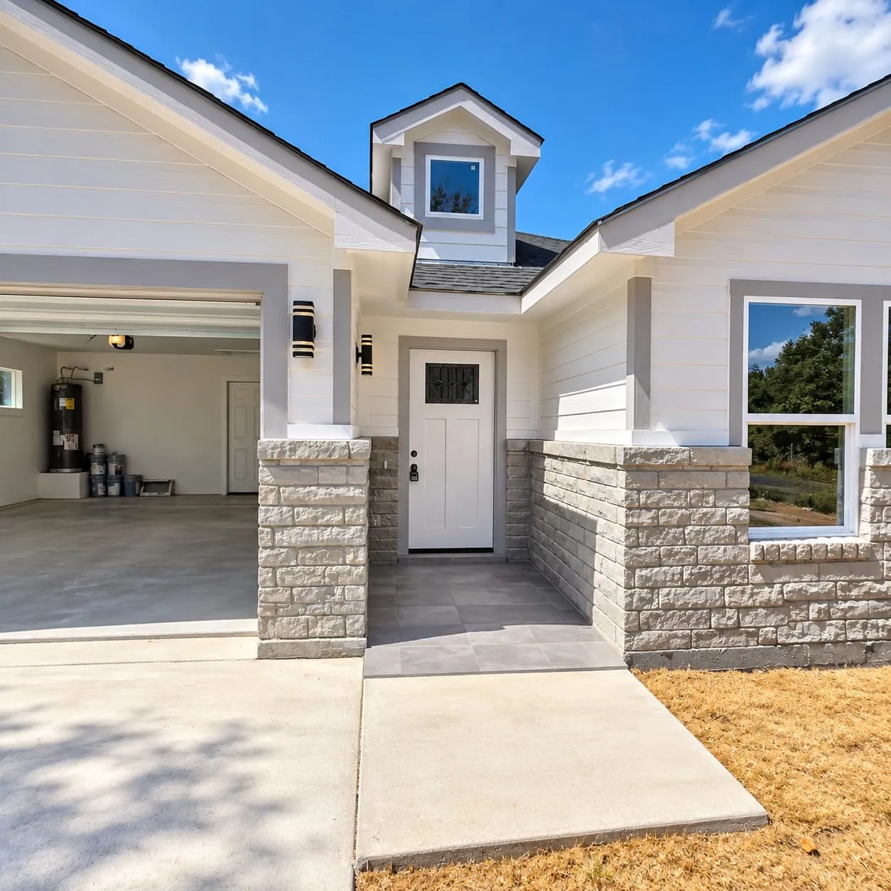 White siding exterior with a stone veneer facade, gabled rooflines, a dormer window, an entry door with decorative glass, and a covered porch with tiled flooring