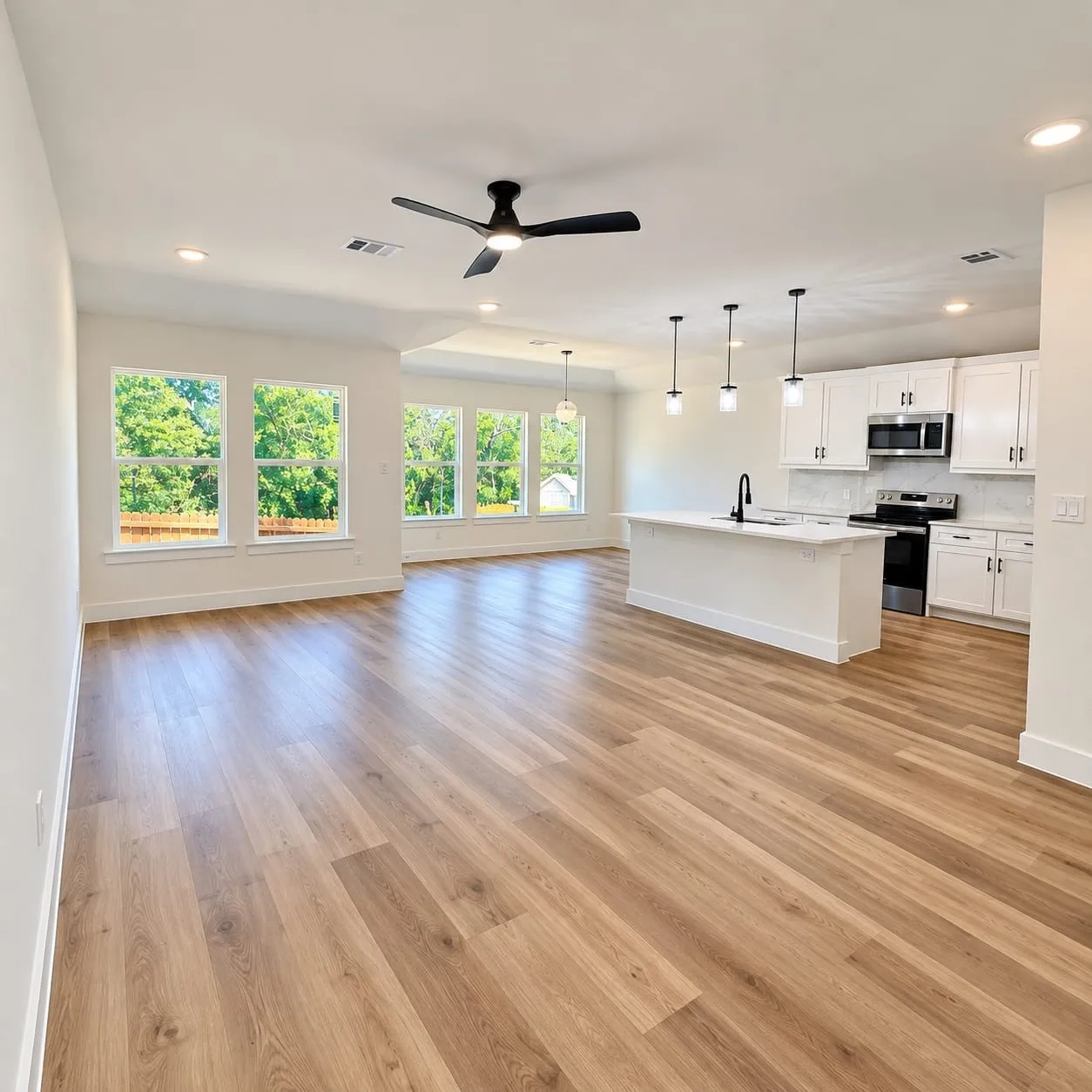 Open-concept living space featuring wood-finish flooring, recessed lighting, and a kitchen with white cabinetry and an island