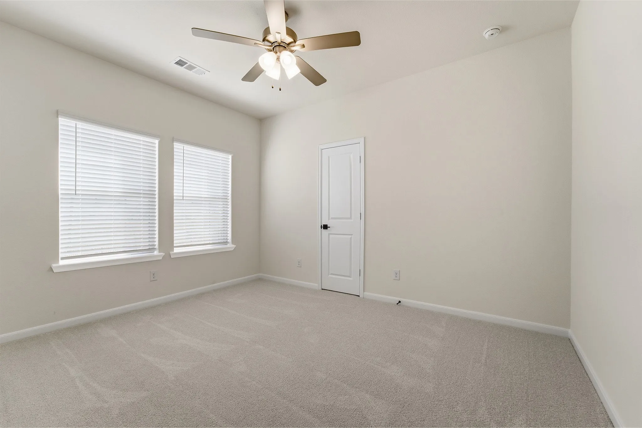 Neutral wall tones, vaulted ceiling, ceiling fan with integrated lighting, two windows with blinds, and light-colored carpeting