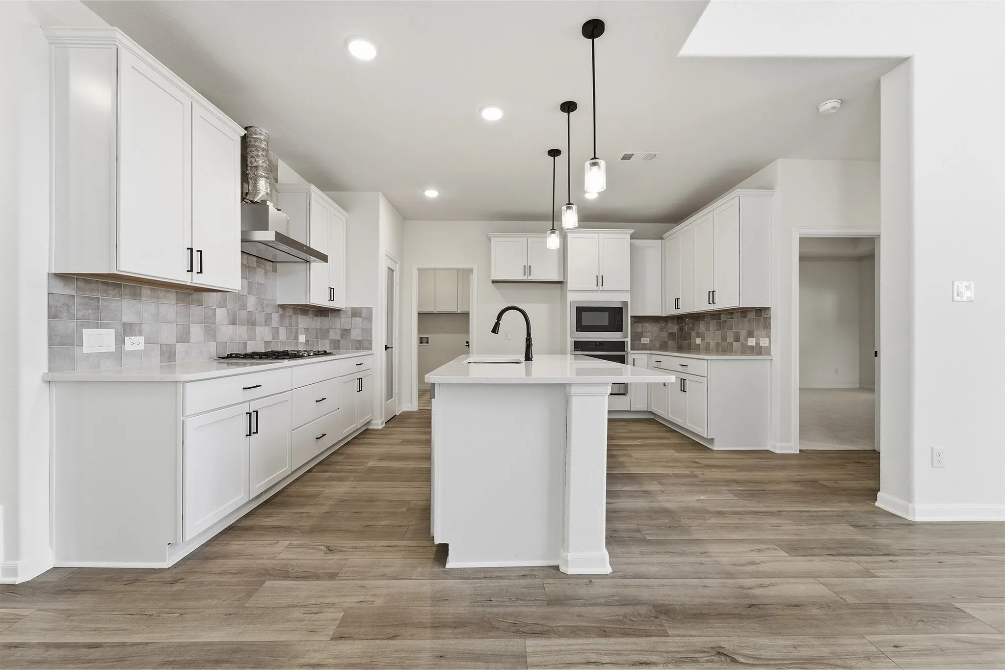 Kitchen featuring white cabinetry, wood-finish flooring, recessed lighting, and a center island with a built-in sink