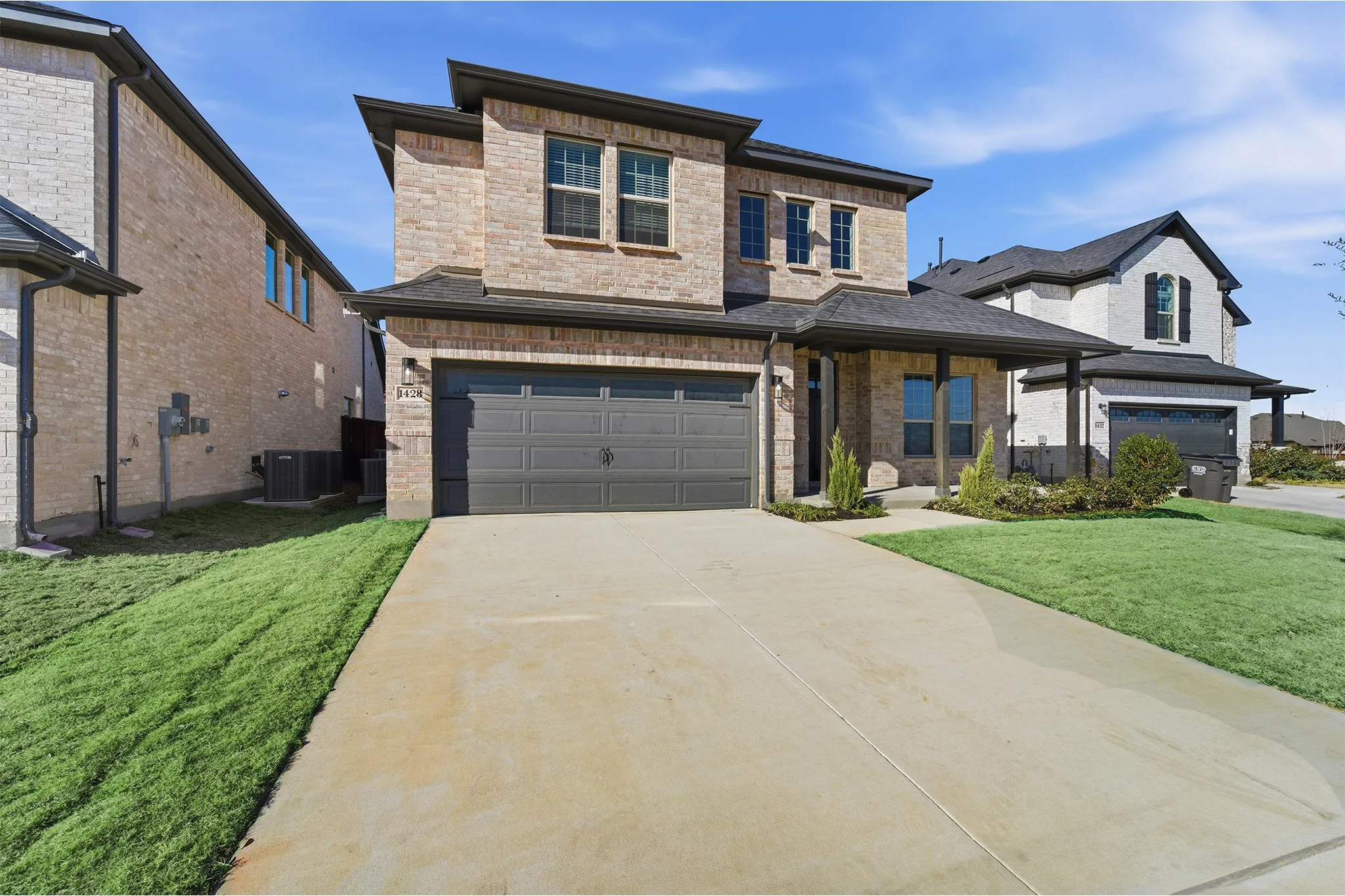 Brick exterior with dark trim accents, featuring a two-car garage and a covered front entry