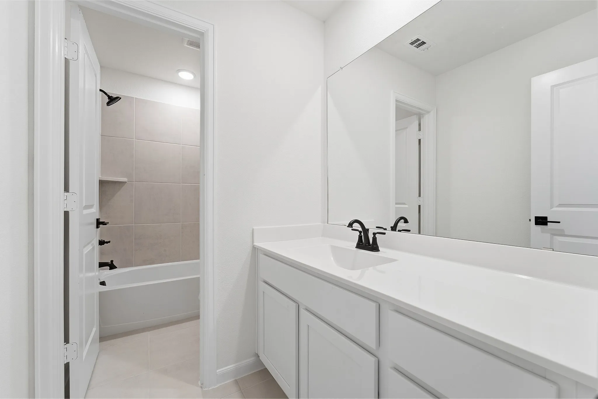 White vanity with integrated sink, expansive vanity mirror, matte black faucet, and white paneled cabinetry