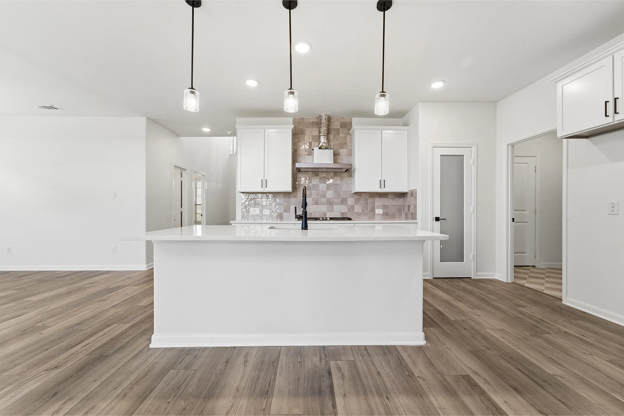 Kitchen featuring a center island, white cabinetry, a tiled backsplash, wood-finish flooring, and pendant lighting