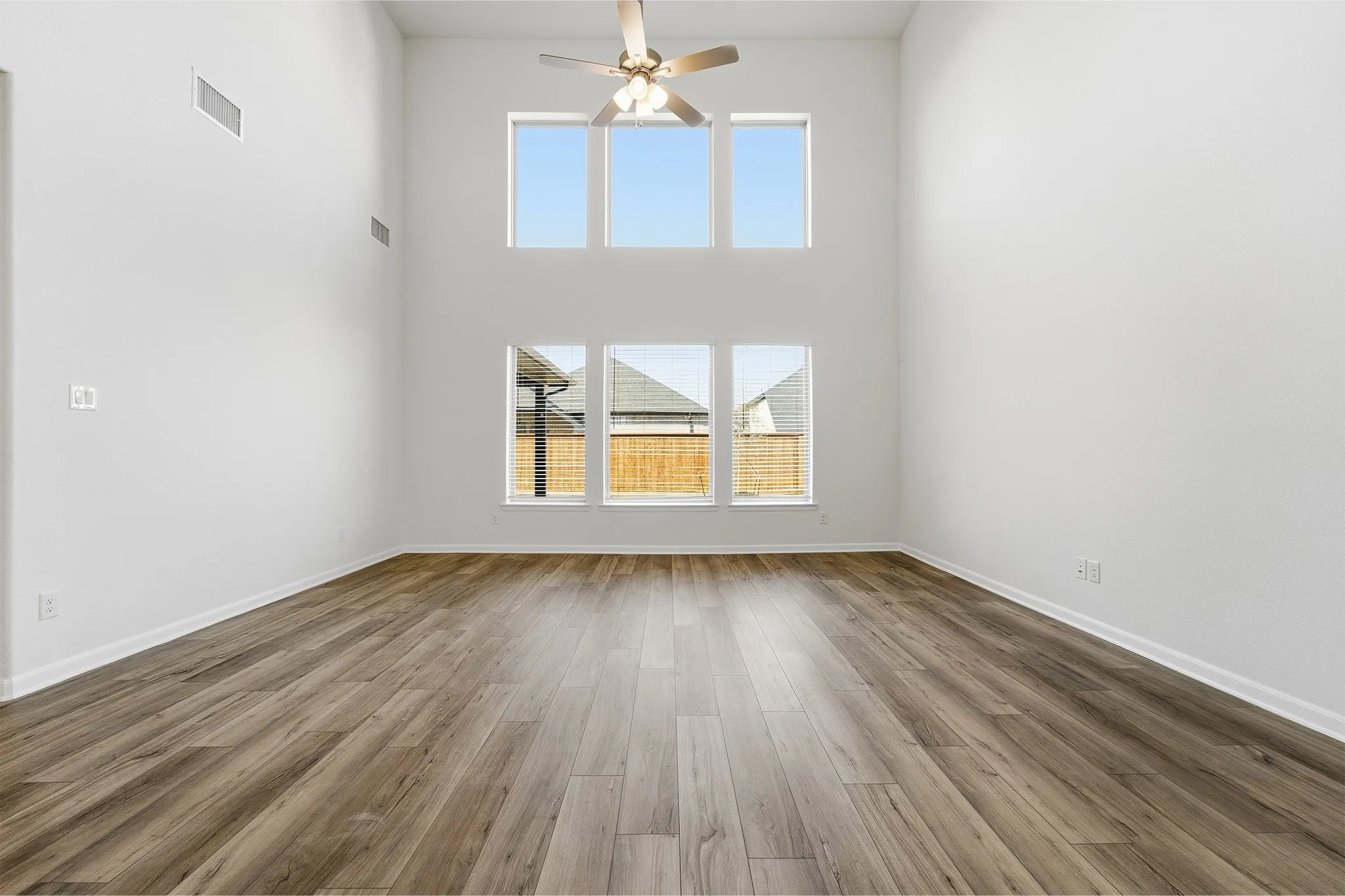 Two-story ceiling, wood-finish flooring, six panel windows, ceiling fan, white wall finish