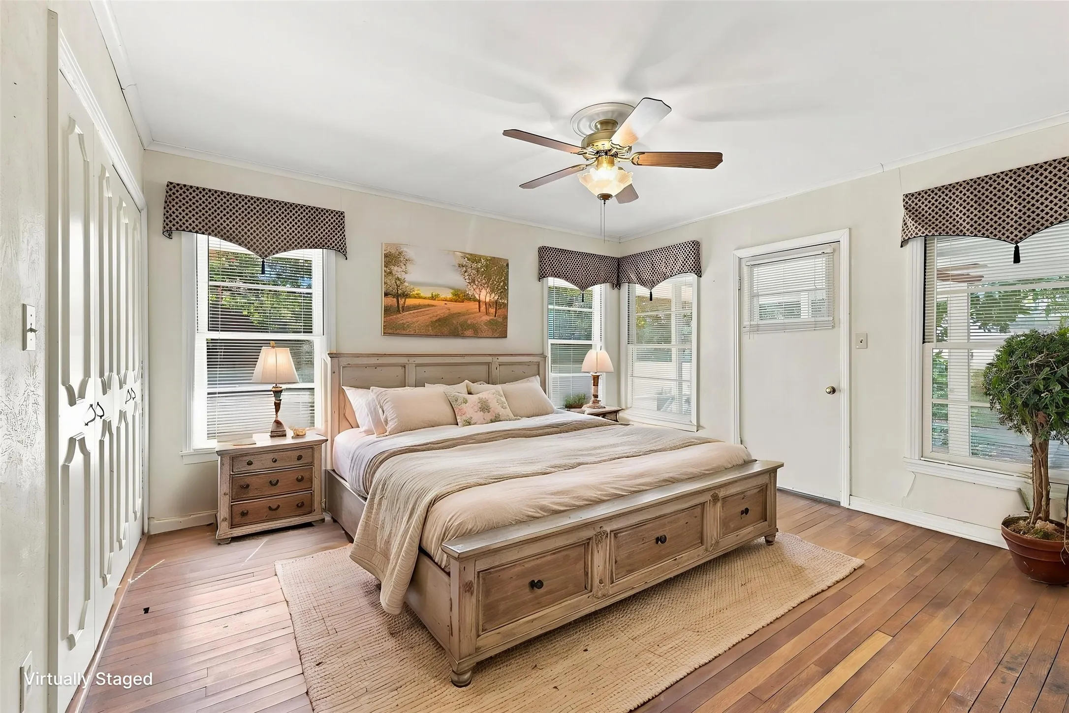 Hardwood flooring with a ceiling fan and multiple windows for natural light. Door exits to screened in porch.