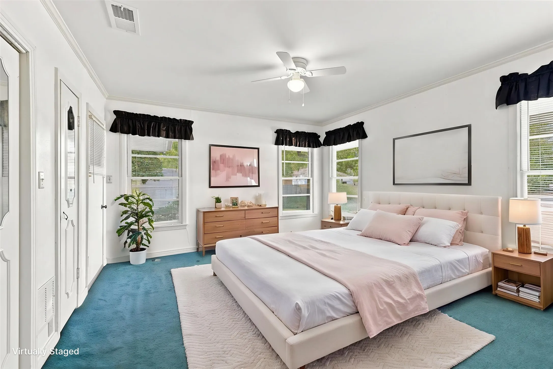 Bright room featuring multiple windows, a ceiling fan, plush carpeting, and white trim.