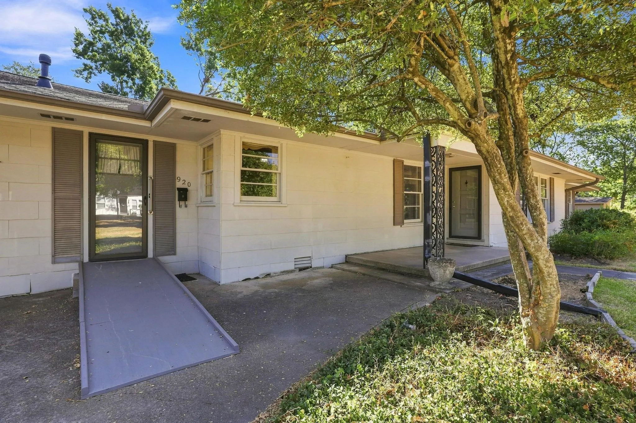 White exterior siding with brown shutters. Ramp leads to the utility room.