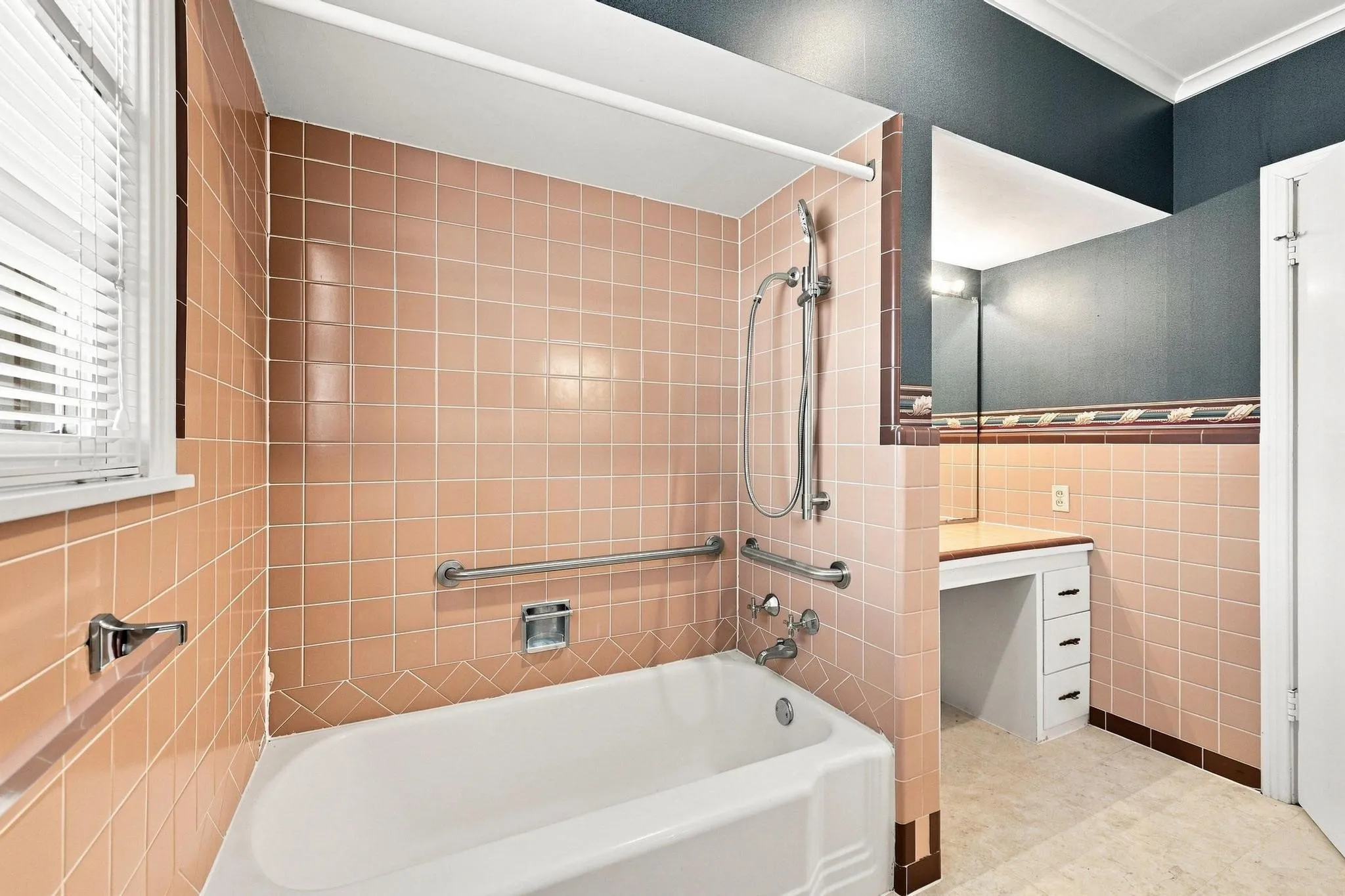 Full bathroom with tile surround, built-in bathtub, chrome fixtures, and a vanity area with built-in storage.
