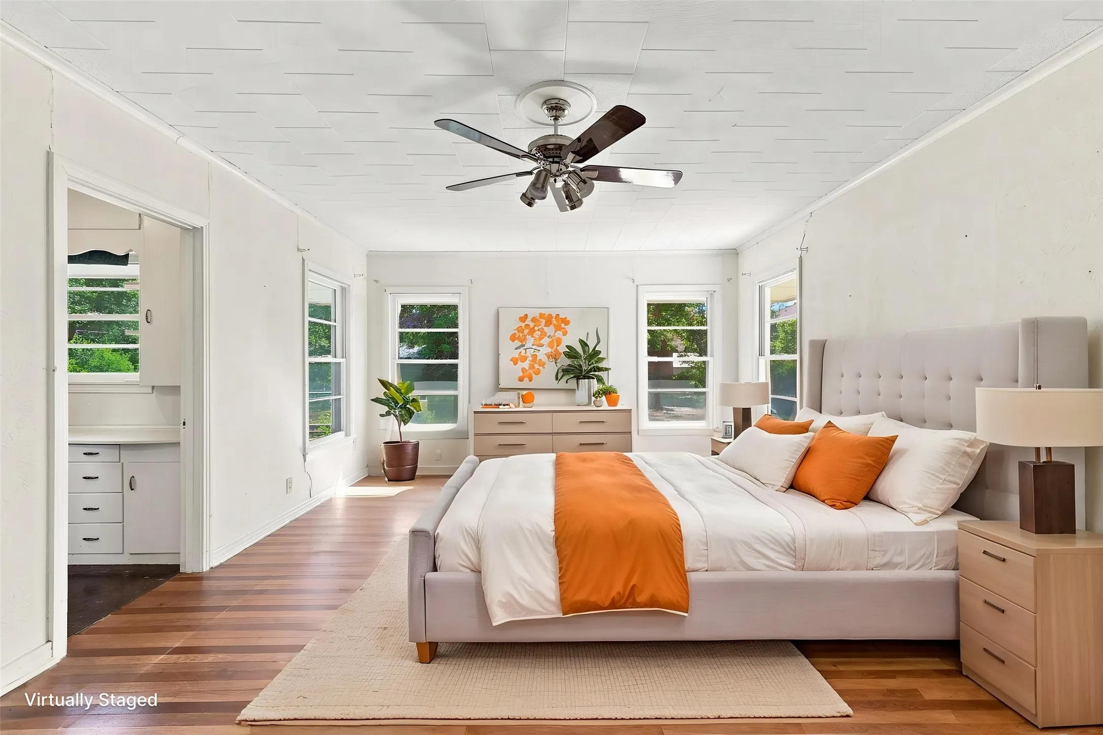 Primary bedroom with ensuite bath, hardwood flooring with white walls,  trim, and ceiling fan.