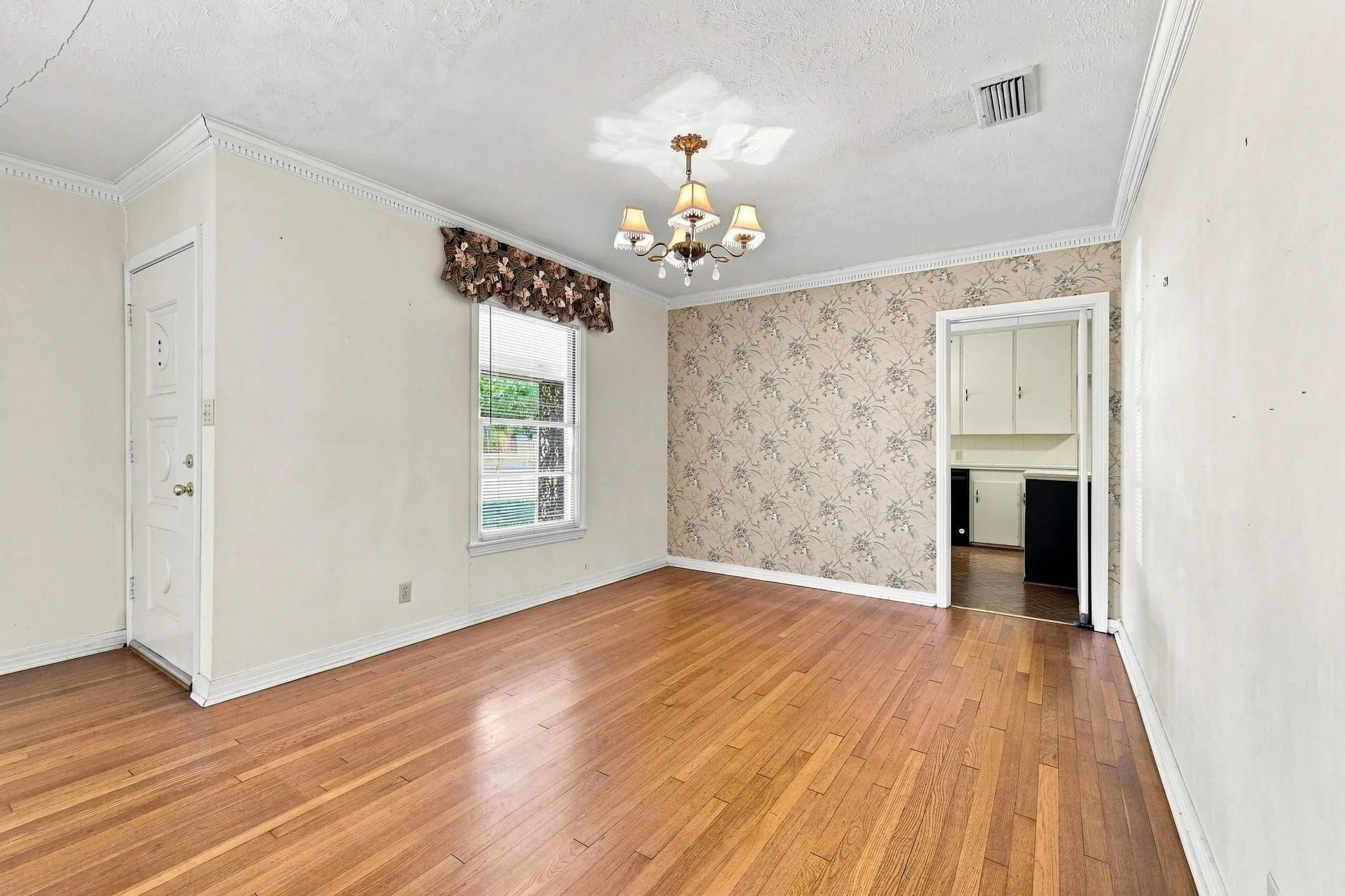 Hardwood flooring, crown molding, and a decorative ceiling light fixture.