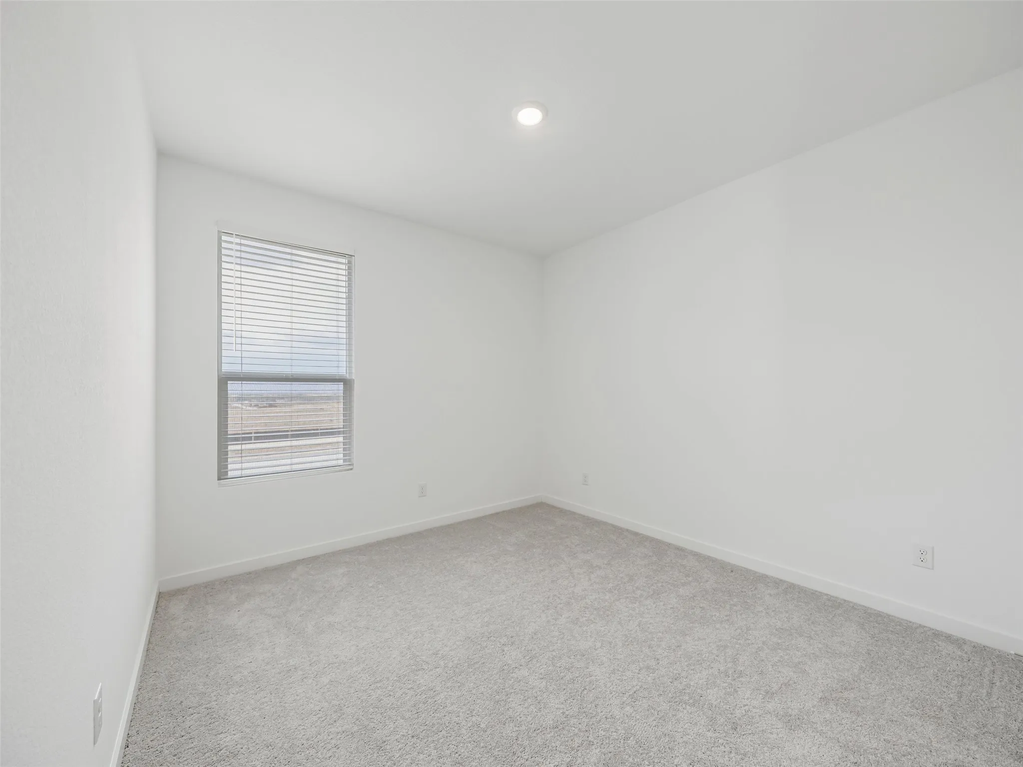 Recessed ceiling lighting, a single window with blinds, and light-toned wall-to-wall carpeting