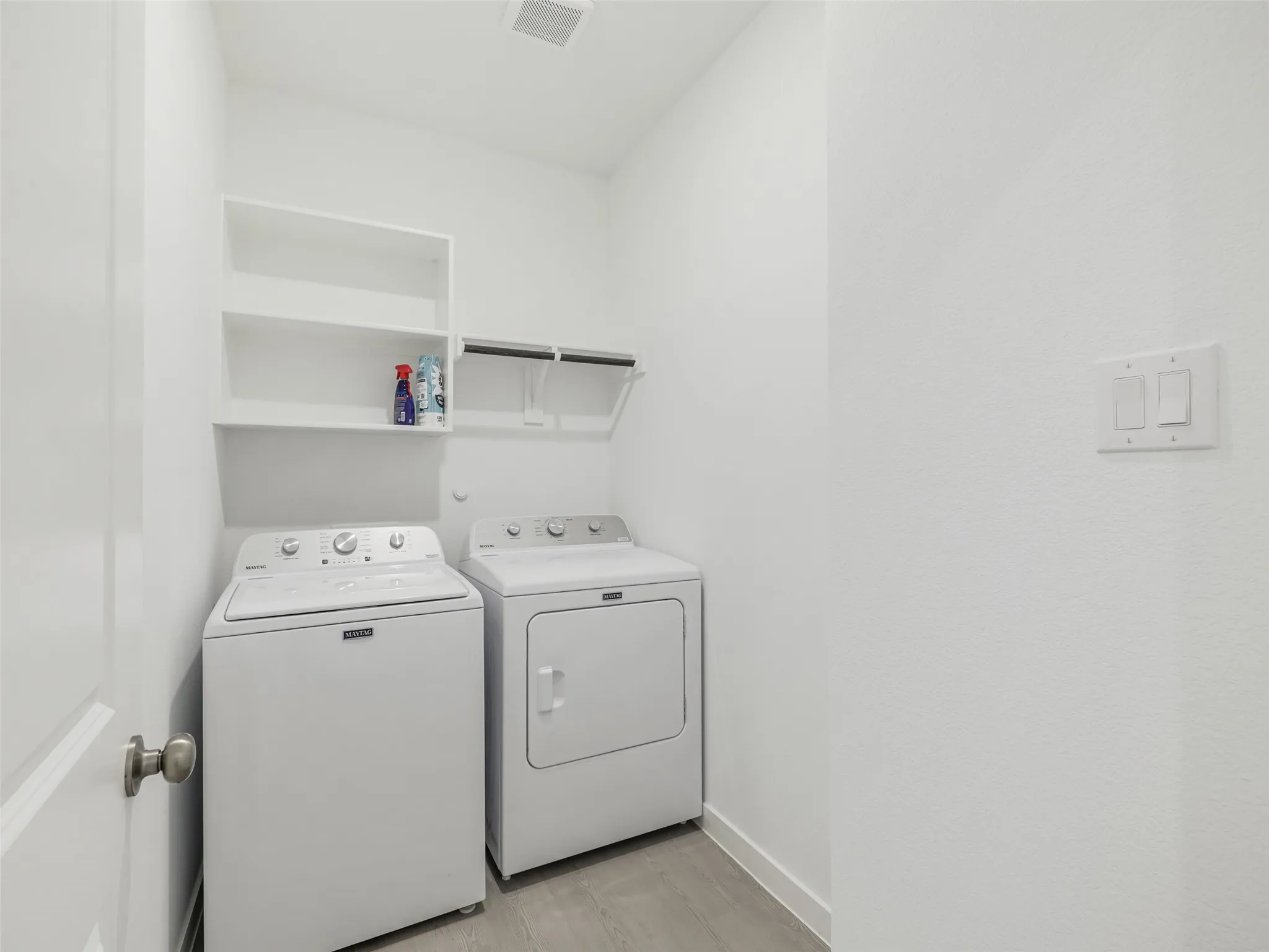 Dedicated laundry space with built-in shelving and wood-finish flooring