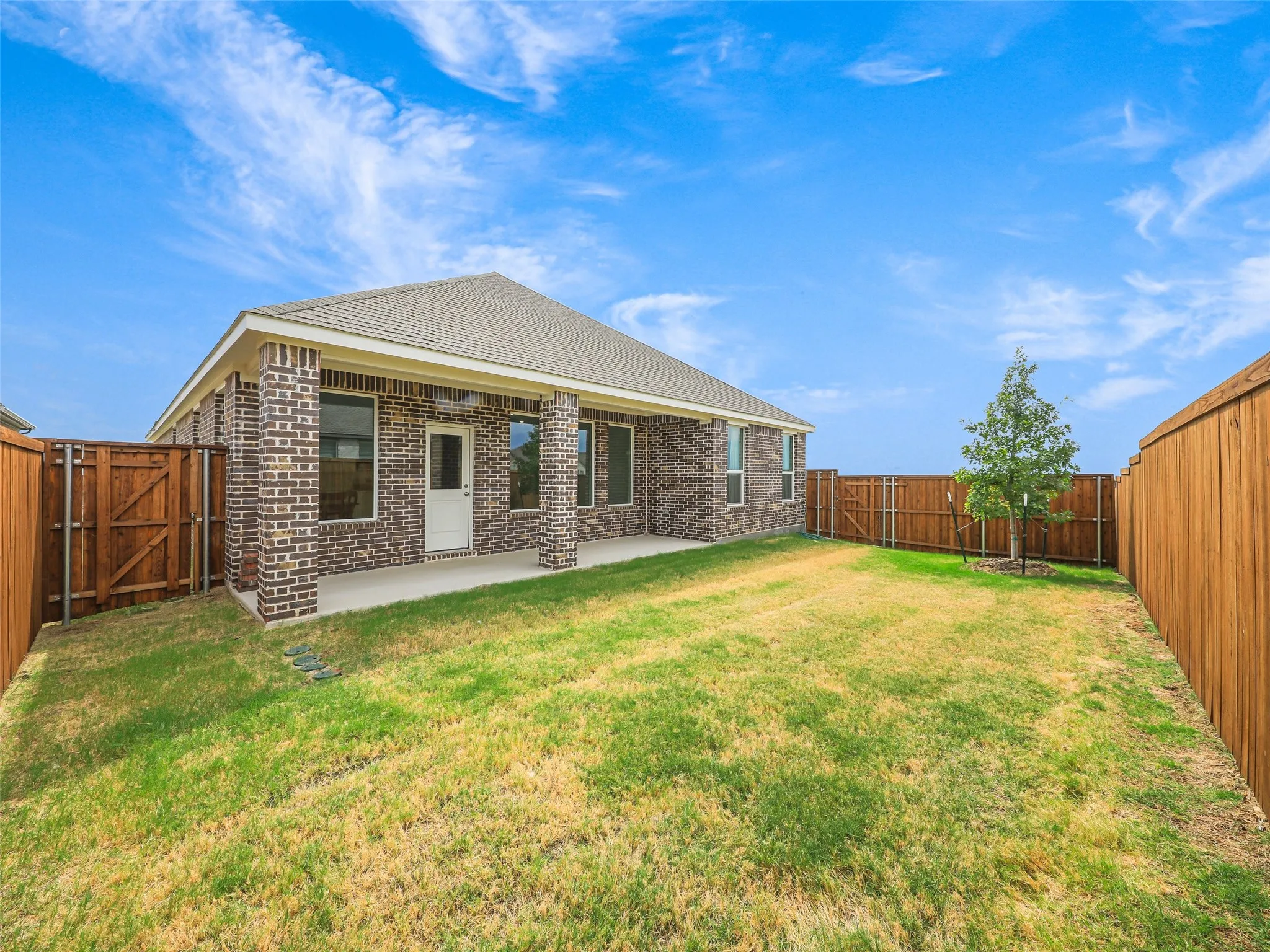 Rear elevation with a covered patio, brick columns, and a fully fenced yard
