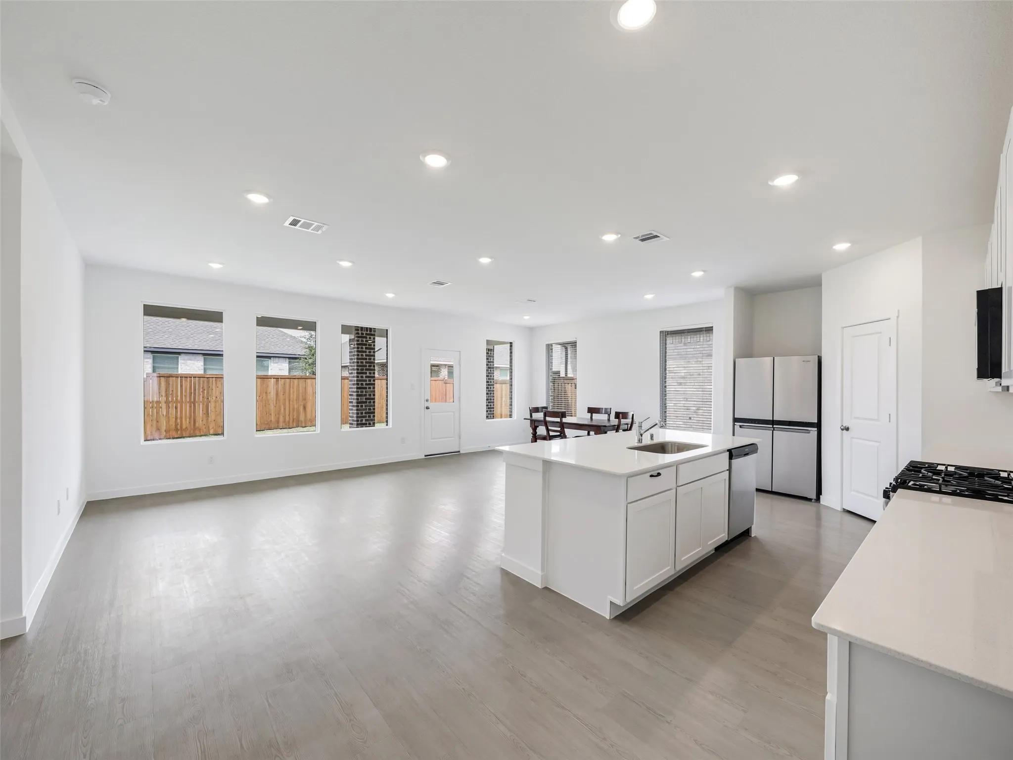 Open-concept living area featuring wood-finish flooring, recessed lighting, and multiple windows