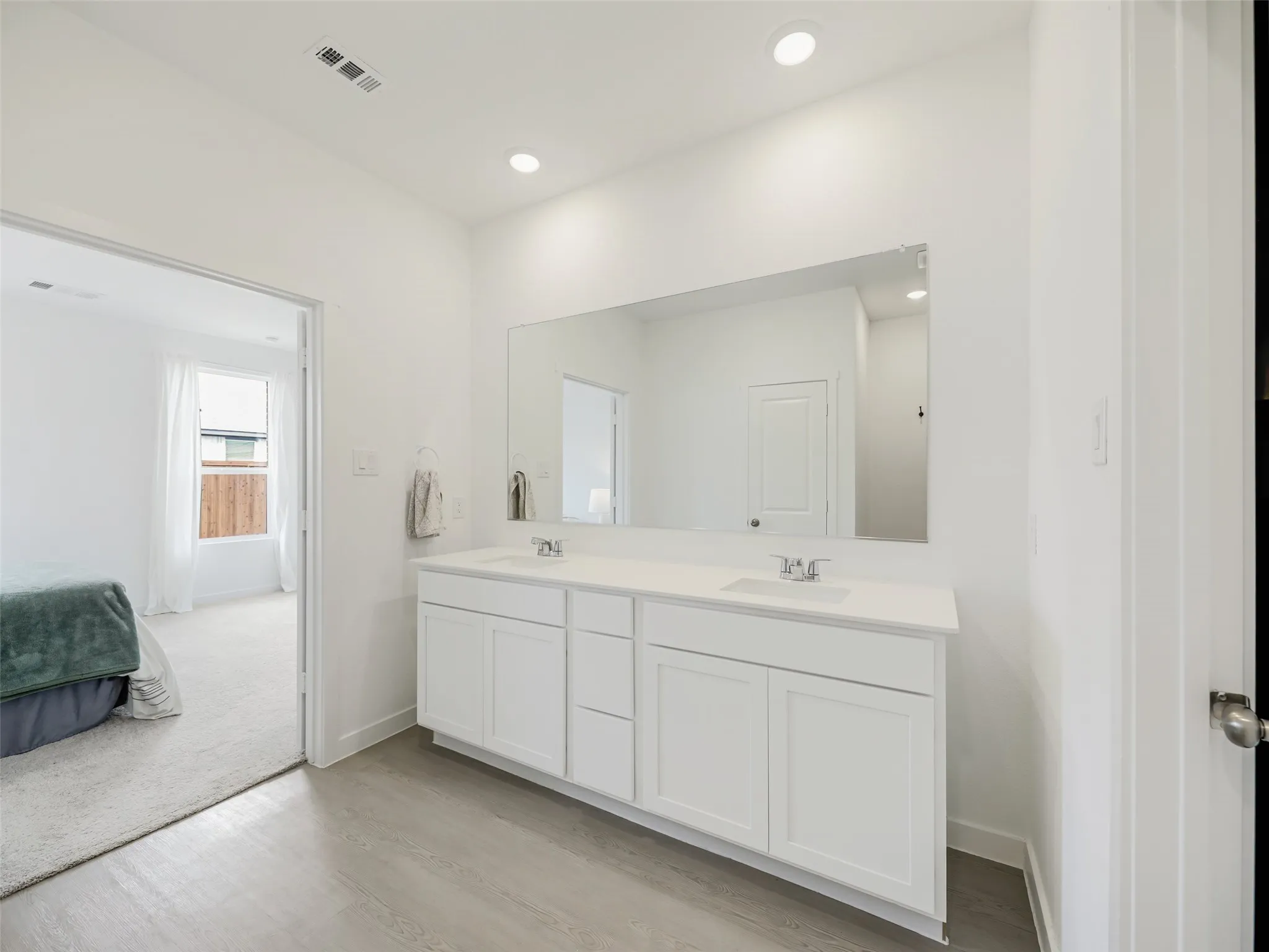 Double vanity with white cabinetry, integrated sinks, white countertop, and a large wall-mounted mirror