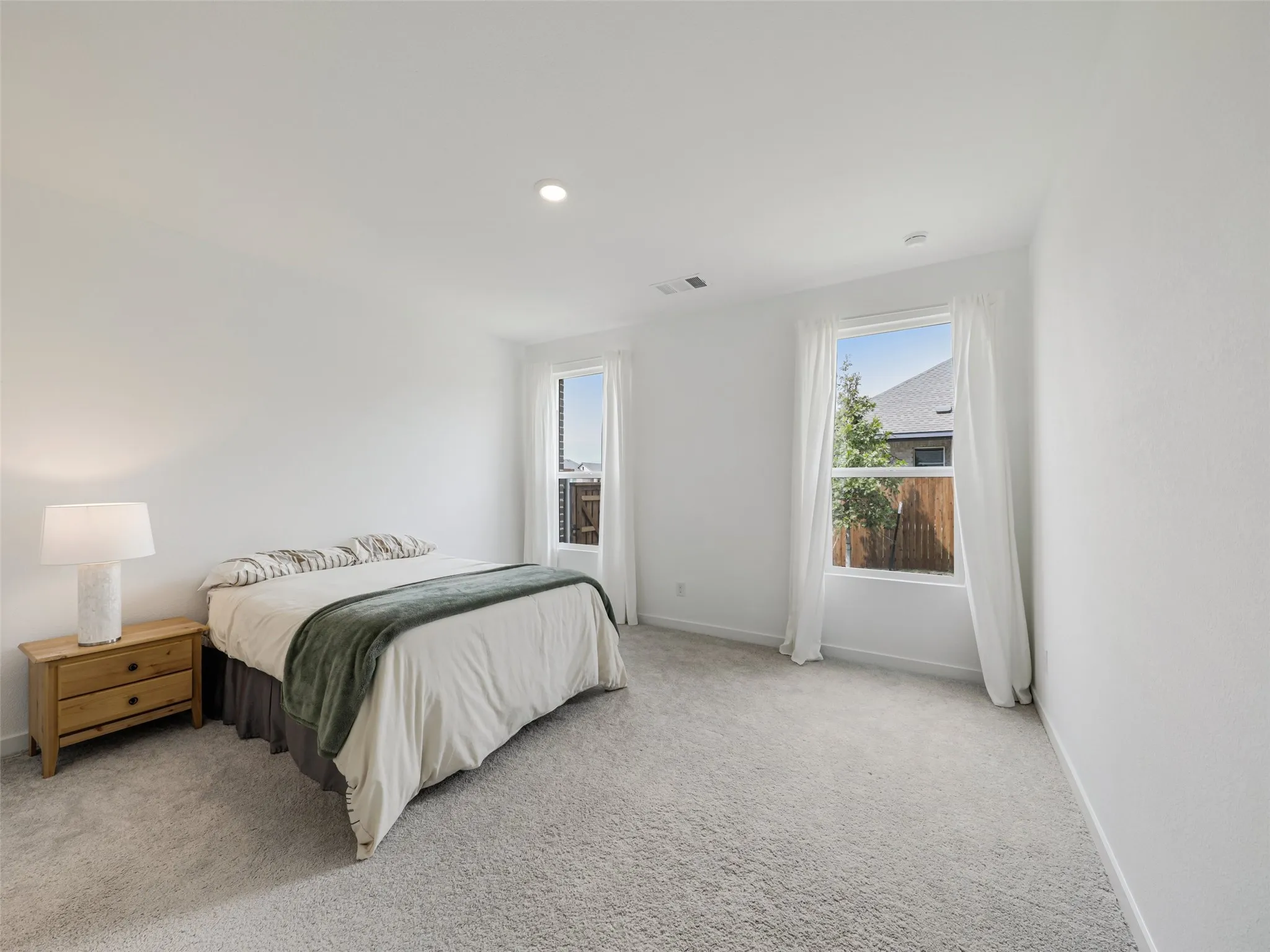 Recessed ceiling lighting, white painted walls, two windows, wall-to-wall carpeting