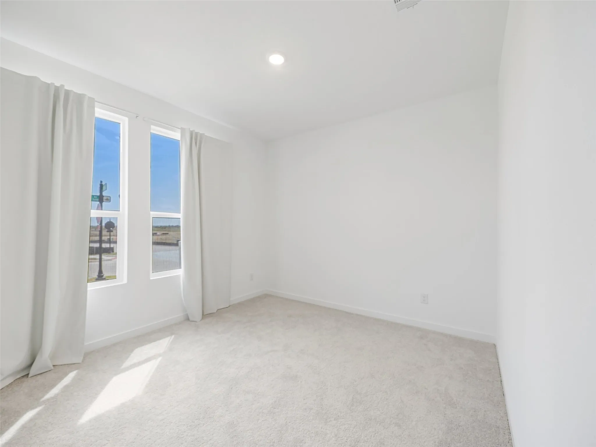 Recessed lighting, light-toned carpeting, two large windows, white walls, and white trim