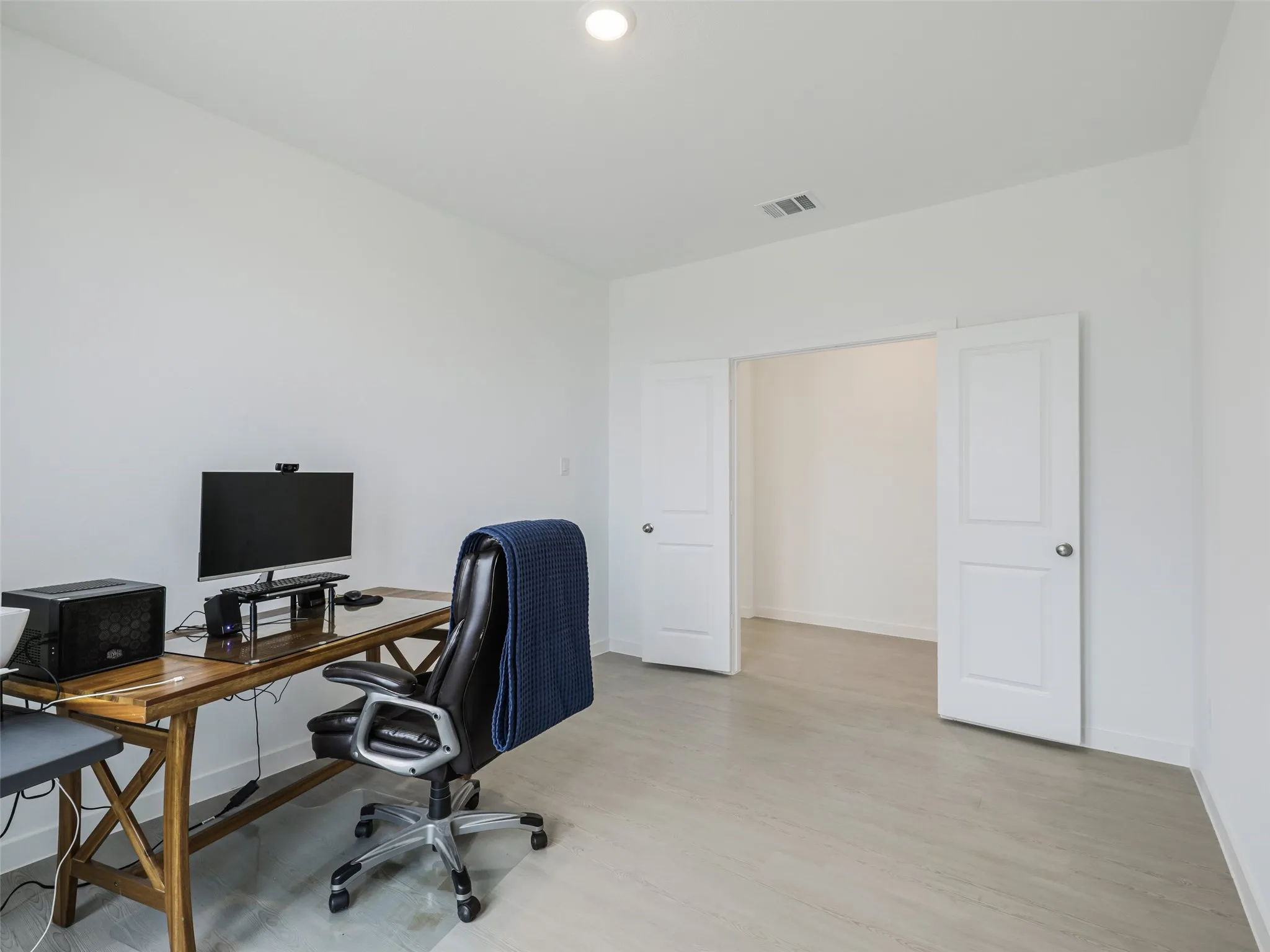 Recessed lighting, light wood-finish flooring, white walls, and a wide entryway with double doors