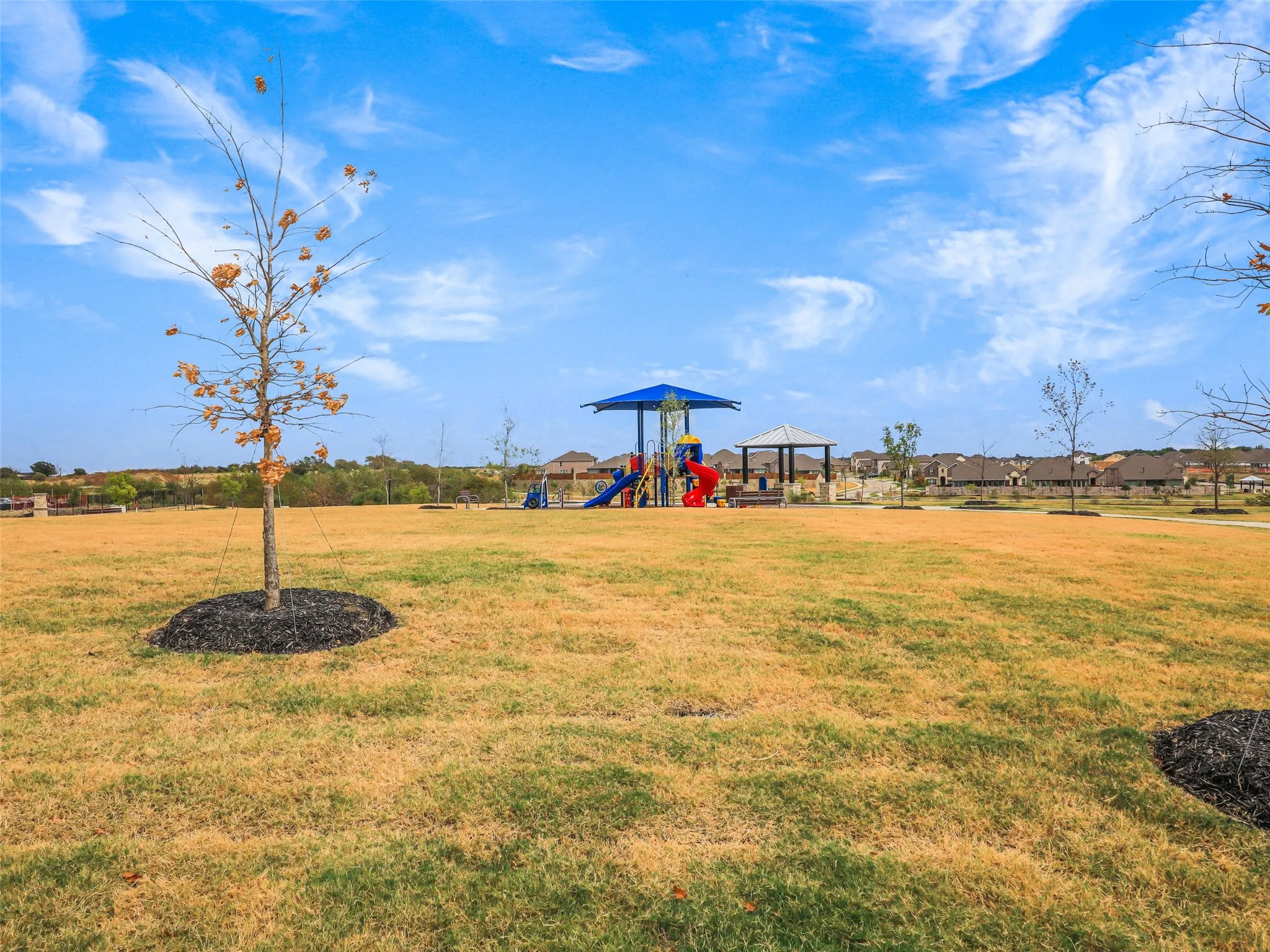 Expansive green space featuring a playground with slides and a covered seating area