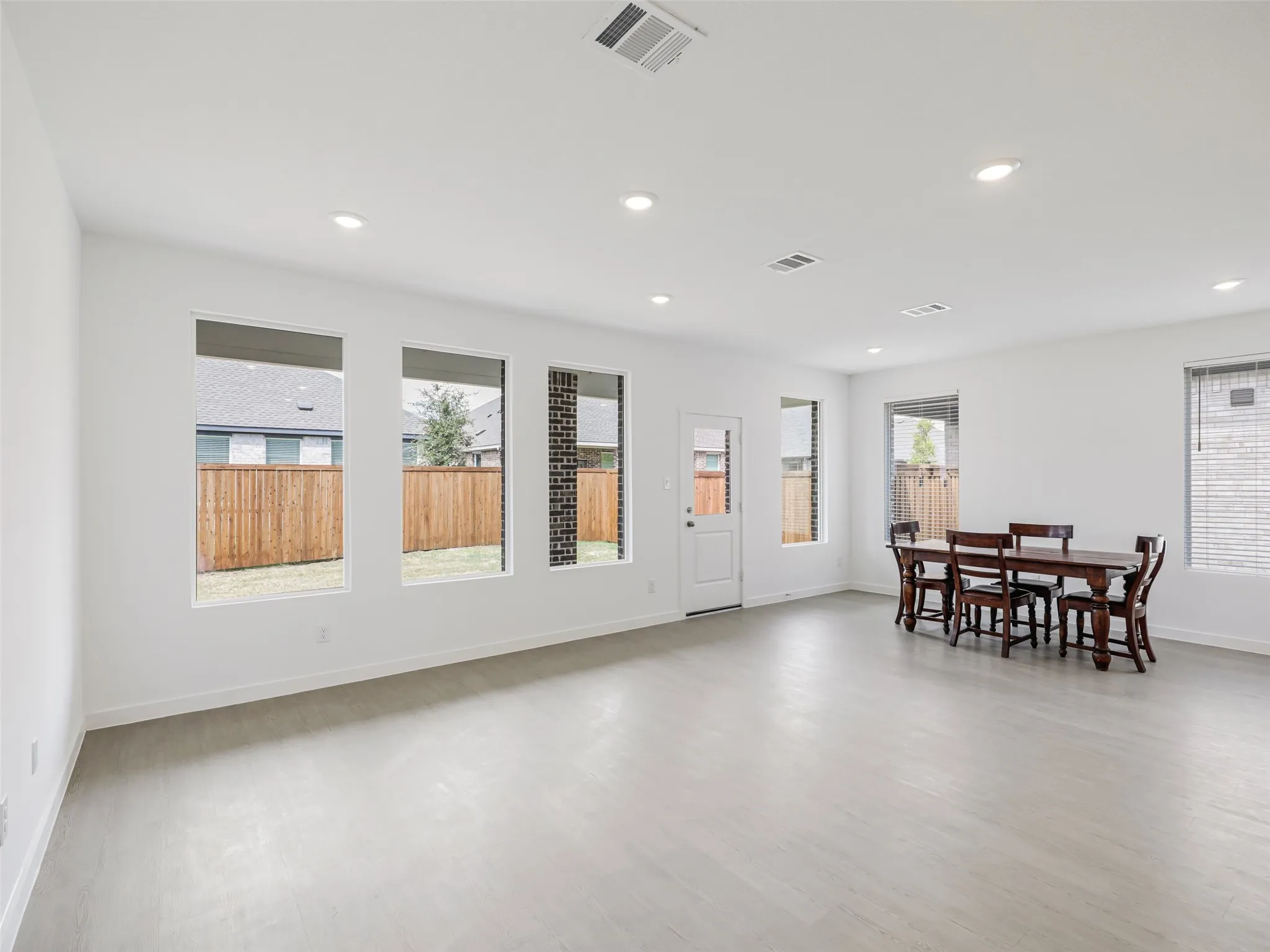 Light wood-finish flooring, recessed lighting, multiple windows, and a rear exterior door