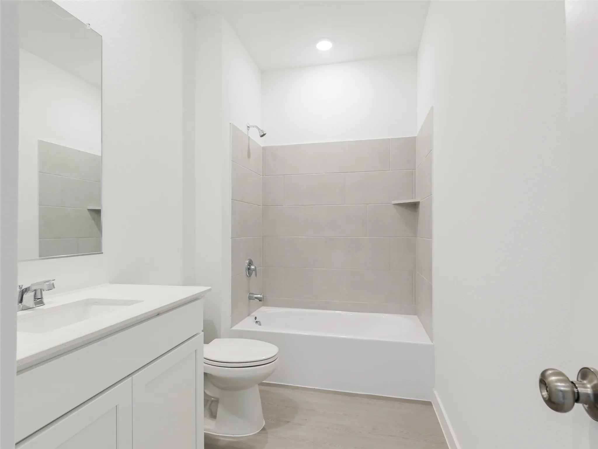 Tub-shower combination with light gray subway tile surround and integrated shelf
