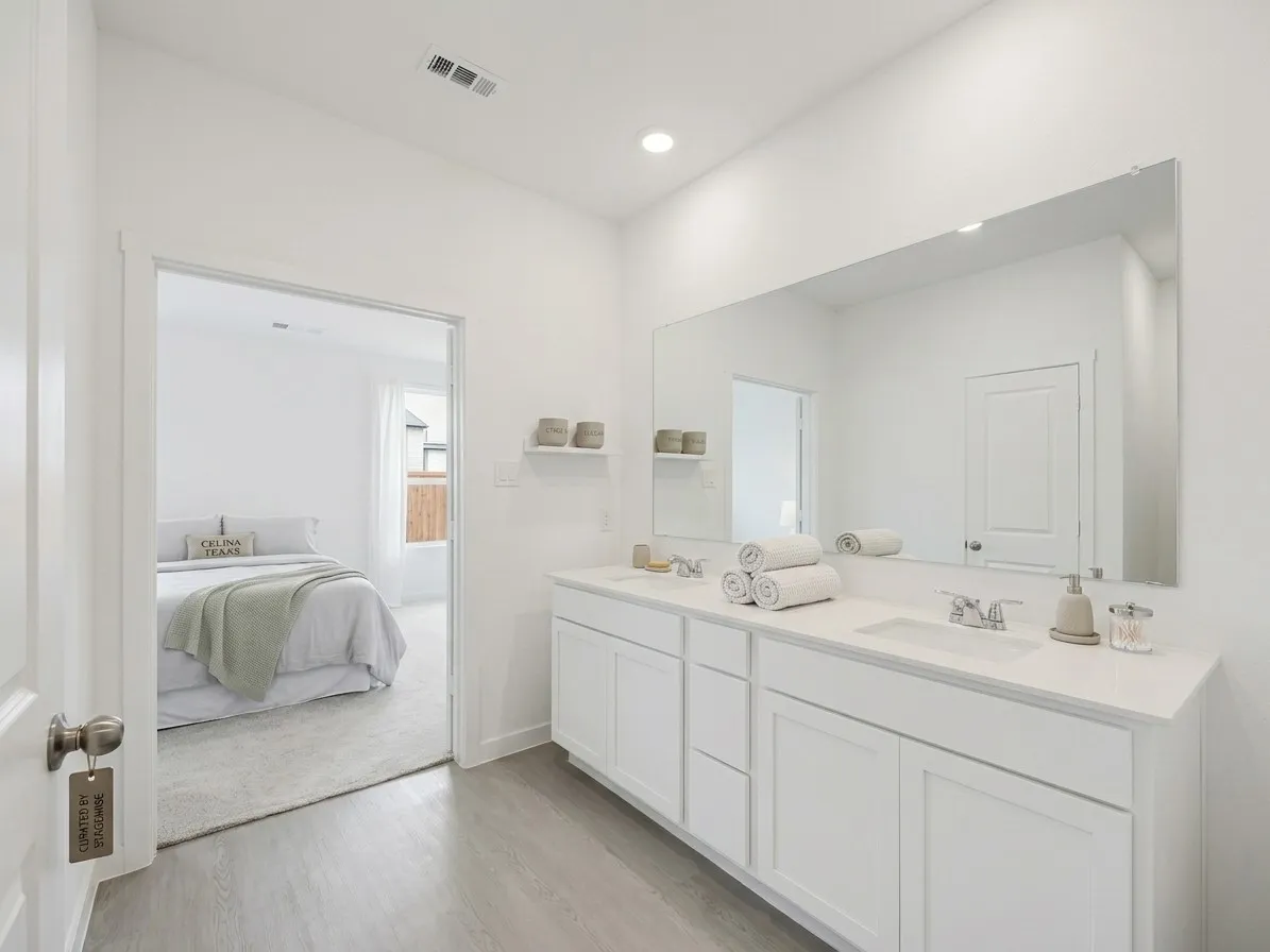 Dual vanity with undermount sinks, white cabinetry, and a full-width mirror