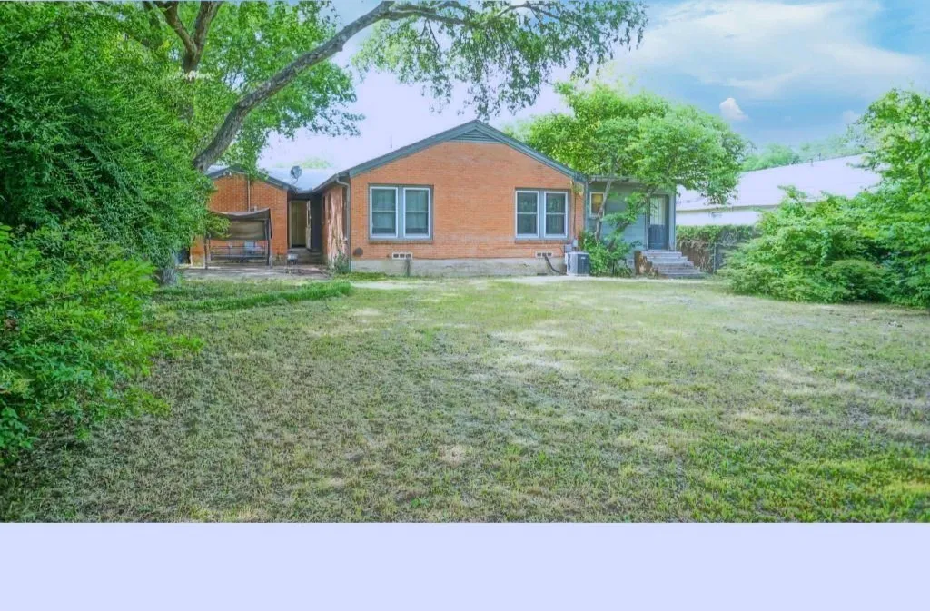 Back of property featuring a lawn and brick siding