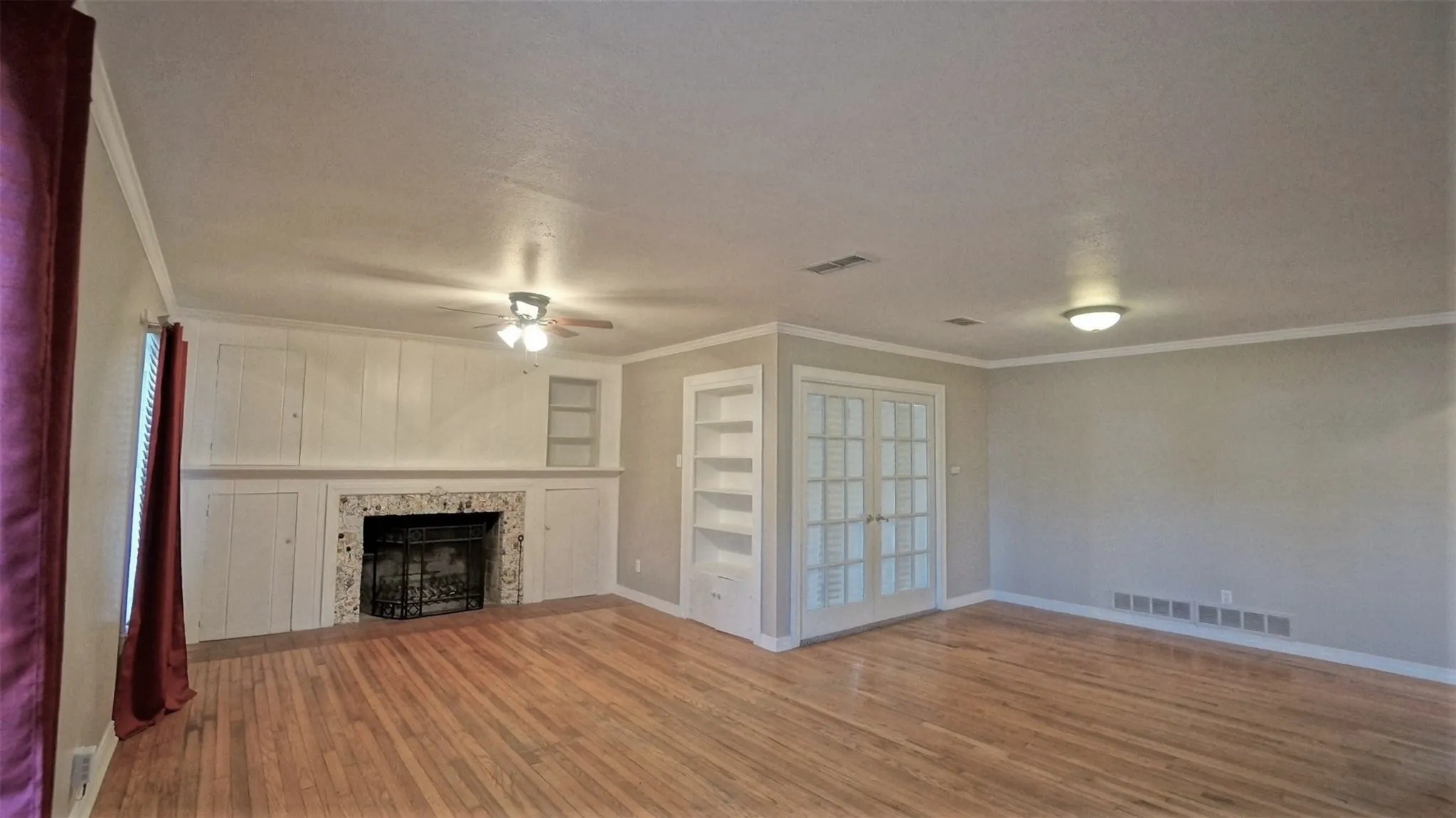 Unfurnished living room featuring ceiling fan, wood finished floors, crown molding, a textured ceiling, and built in features