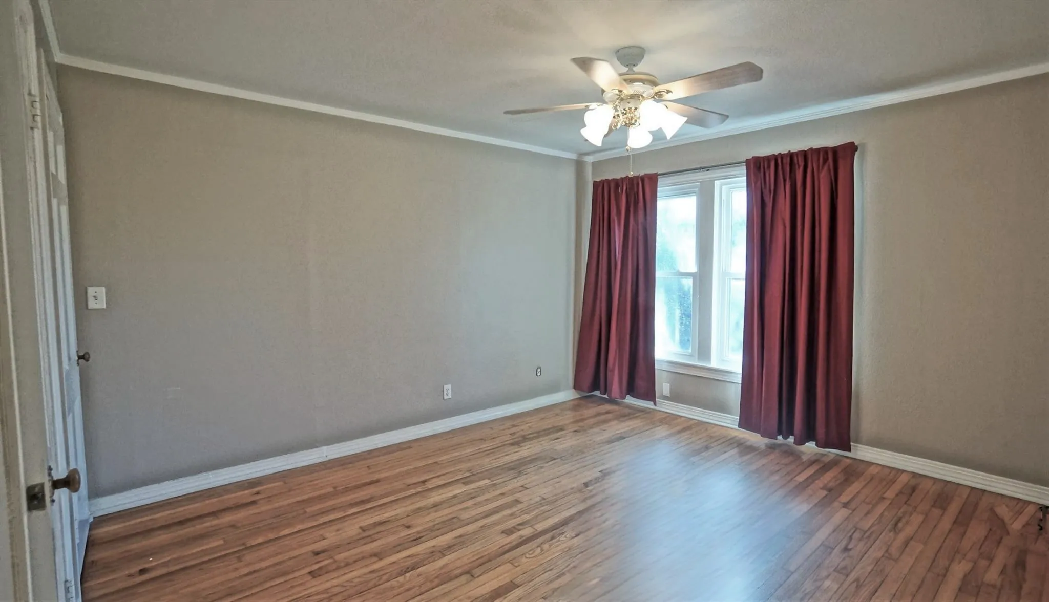 Spare room featuring wood finished floors, a ceiling fan, and ornamental molding