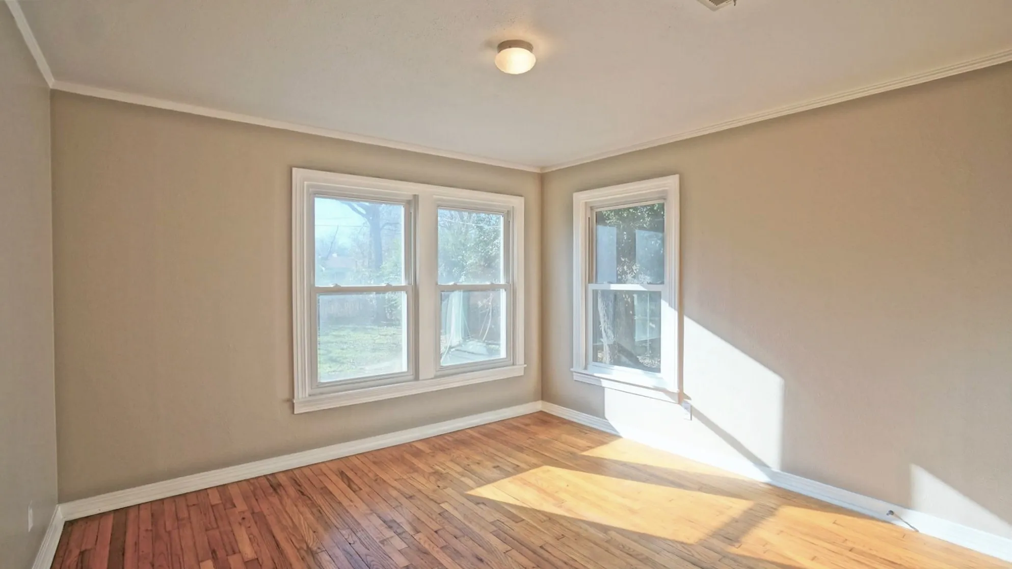 Empty room with plenty of natural light, wood finished floors, and ornamental molding
